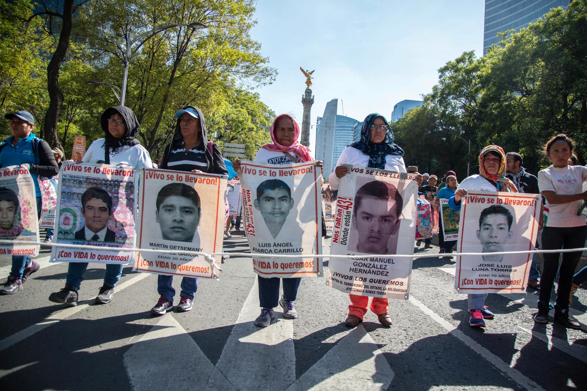 Kvinnor håller upp bilder av de 43 försvunna studenterna vid en protest i Mexico City i maj i år.