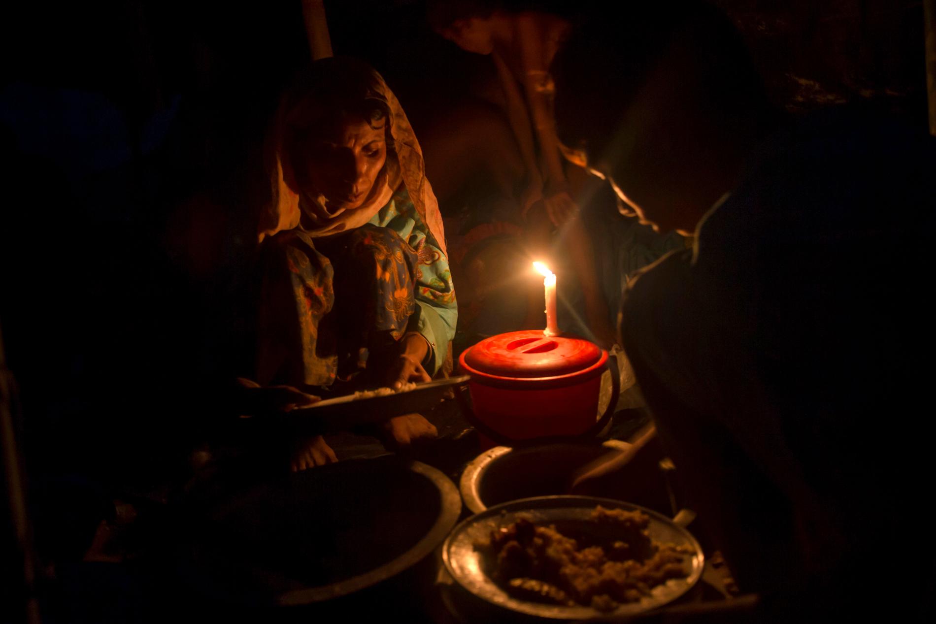 En rohingysk kvinna lagar mat till sin son i ett temporärt skydd i ett flyktingläger i Bangladesh.