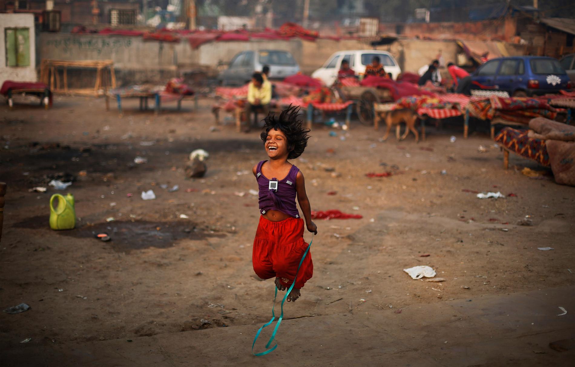 En flicka leker med ett hopprep intill en tillfällig bosättning i New Delhi, Indien. Landet har länge varit det land i världen med flest antal fattiga, men på senare år har andelen som lever i fattigdom minskat.