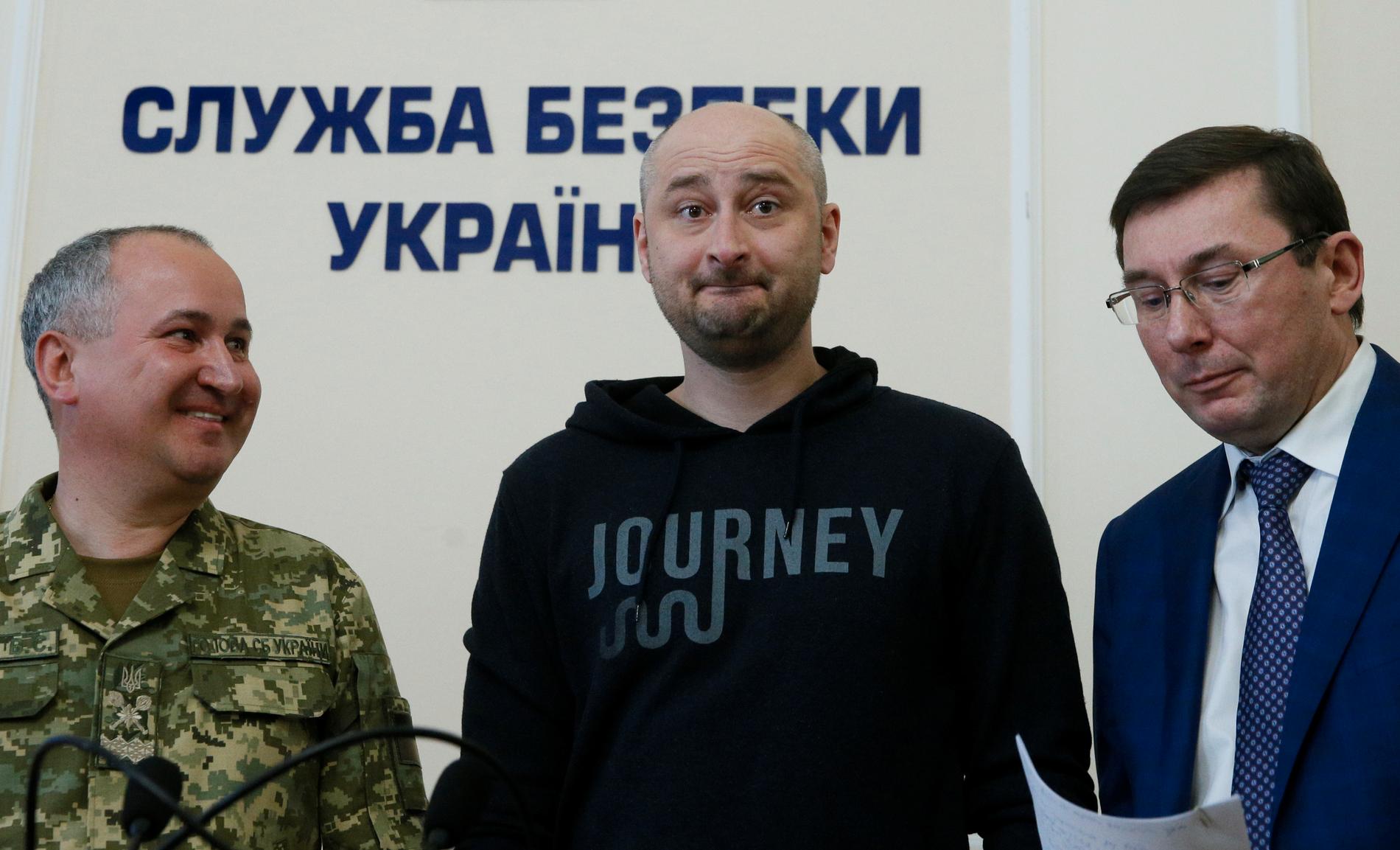 Den ryske journalisten Arkadij Babtjenko (i mitten ) som i tisdags rapporterades mördad – har dykt upp vid liv på en presskonferens i den ukrainska huvudstaden Kiev. Här står han mellan den ryske chefsåklagaren (till höger) och chefen för den ukrainska säkerhetstjänsten (till vänster).