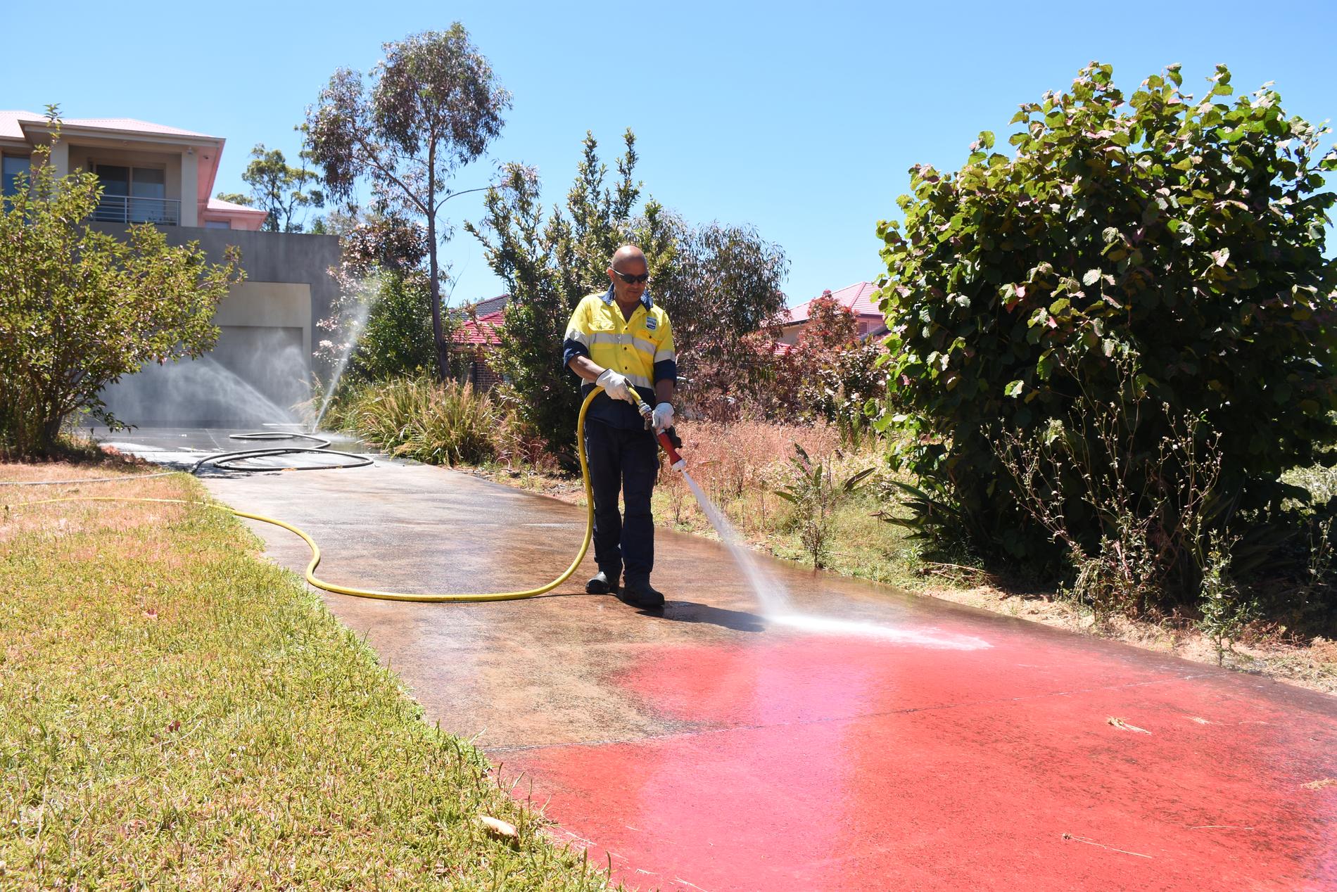 Det rosa medlet som användes vid vattenbombningen spolas bort dagen efter att brandrisken i delar av New South Wales nådde katastrofläge.
