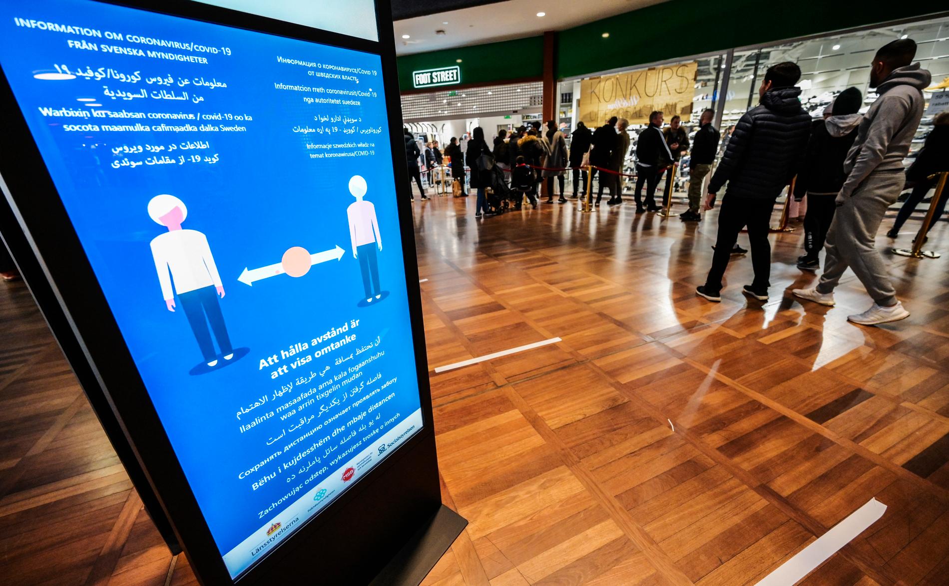 Att hålla avstånd är att visa omtanke, lyder myndighetsinformationen i Triangelns köpcentrum i Malmö. I bakgrunden köar människor till en utförsäljning. Arkivbild.