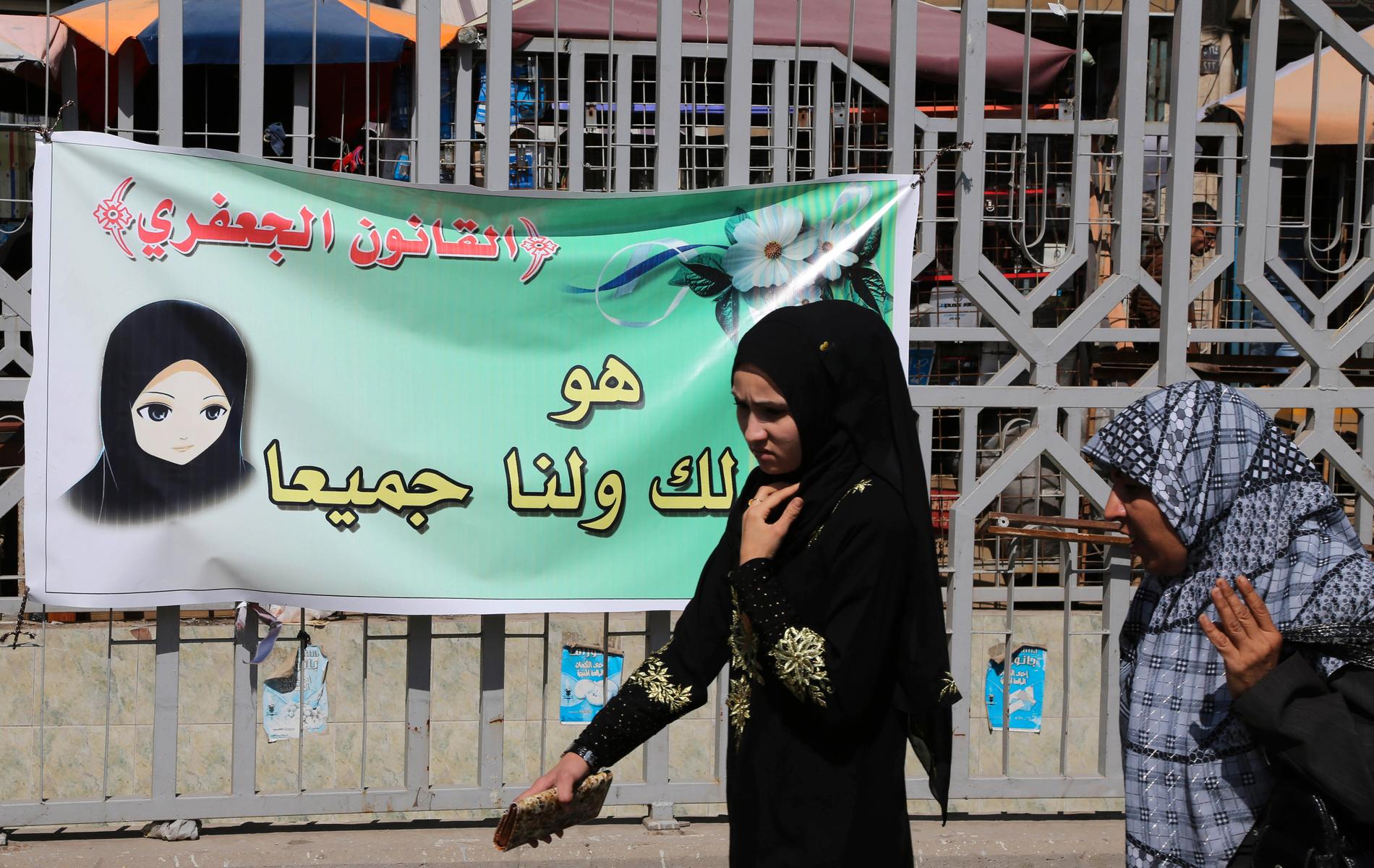 Flicka passerar poster för Jaafari-lagen i Irak.