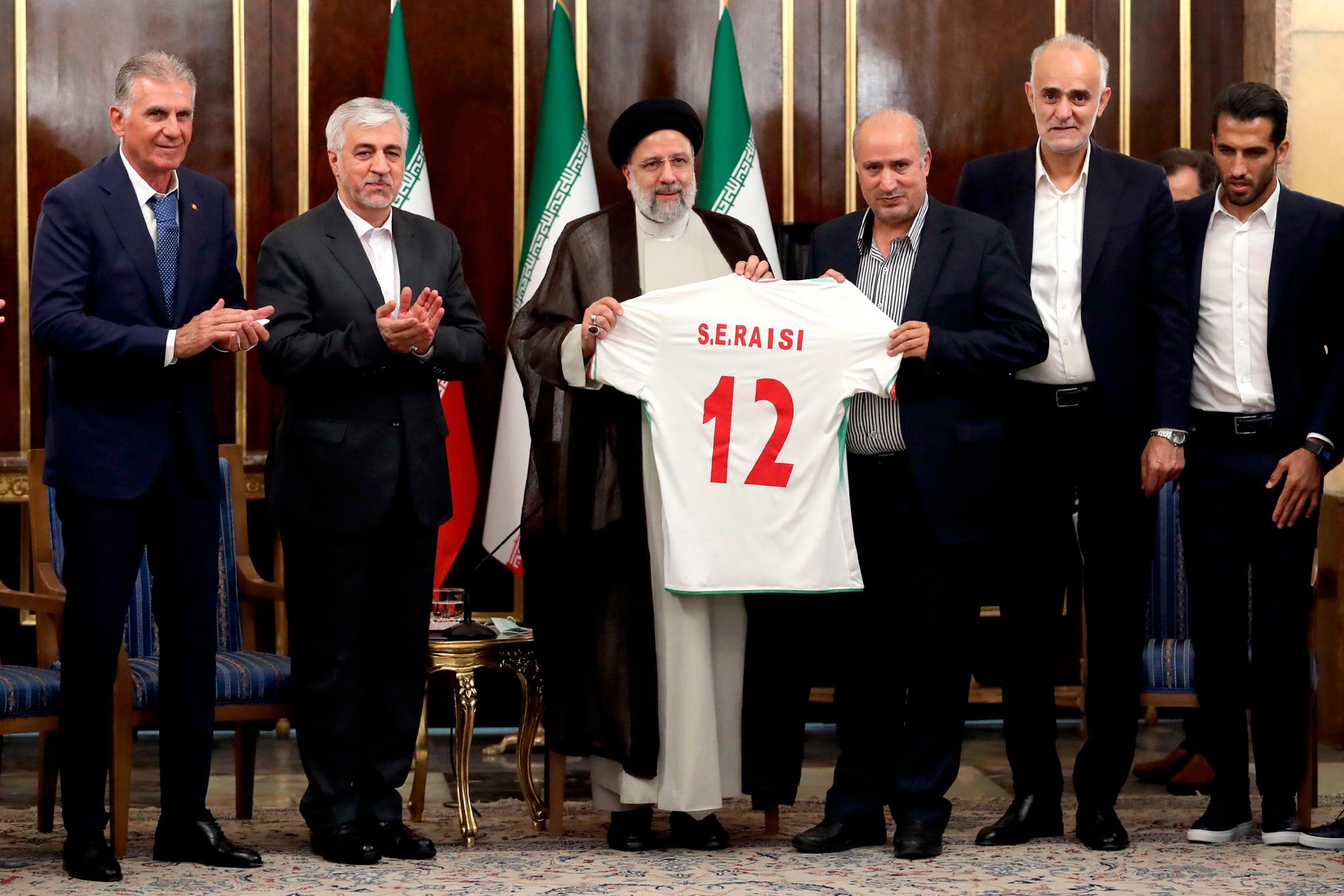 Irans president, tredje till vänster, får en landslagströja under ett möte i november 2022. Andra till vänster är idrottsminister Hamid Sajjad.