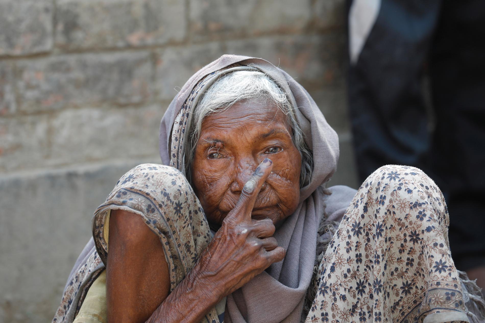 En äldre kvinna i Varanasi visar den bläckmärkning på fingret som visar att hon röstat i det indiska parlamentsvalet.