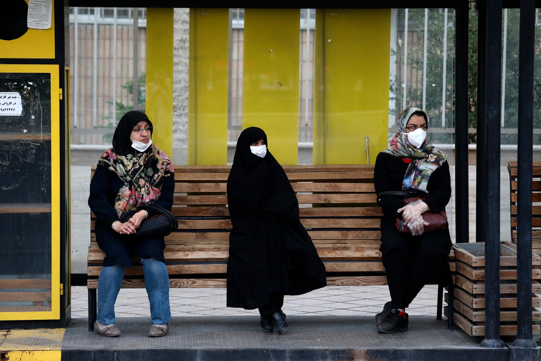 Kvinnor i iranska Zanjan väntar på bussen iförda ansiktsmasker, vilka numer är obligatoriska i offentligheten.