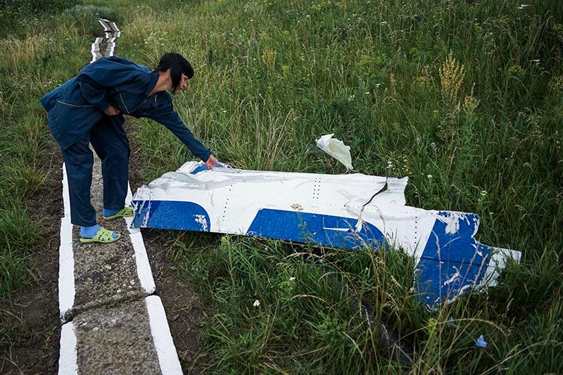 En kvinna som jobbar på det lokala vattenverket undersöker en del av det nedskjutna MH17-planet som inte tagits bort efter katastrofen.