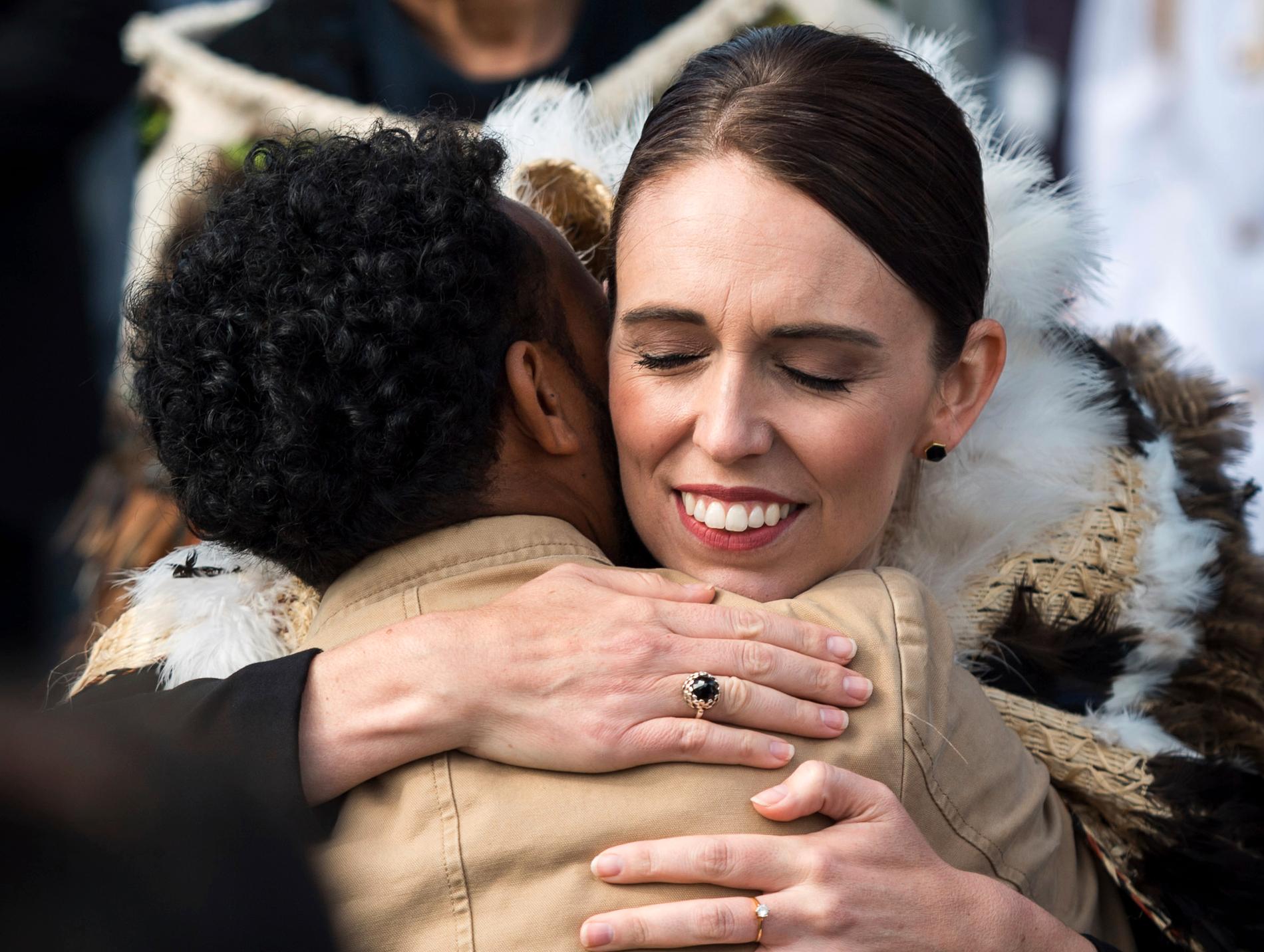 Jacinda Ardern omfamnar en besökare under ceremonin i Hagley Park i Christchurch.