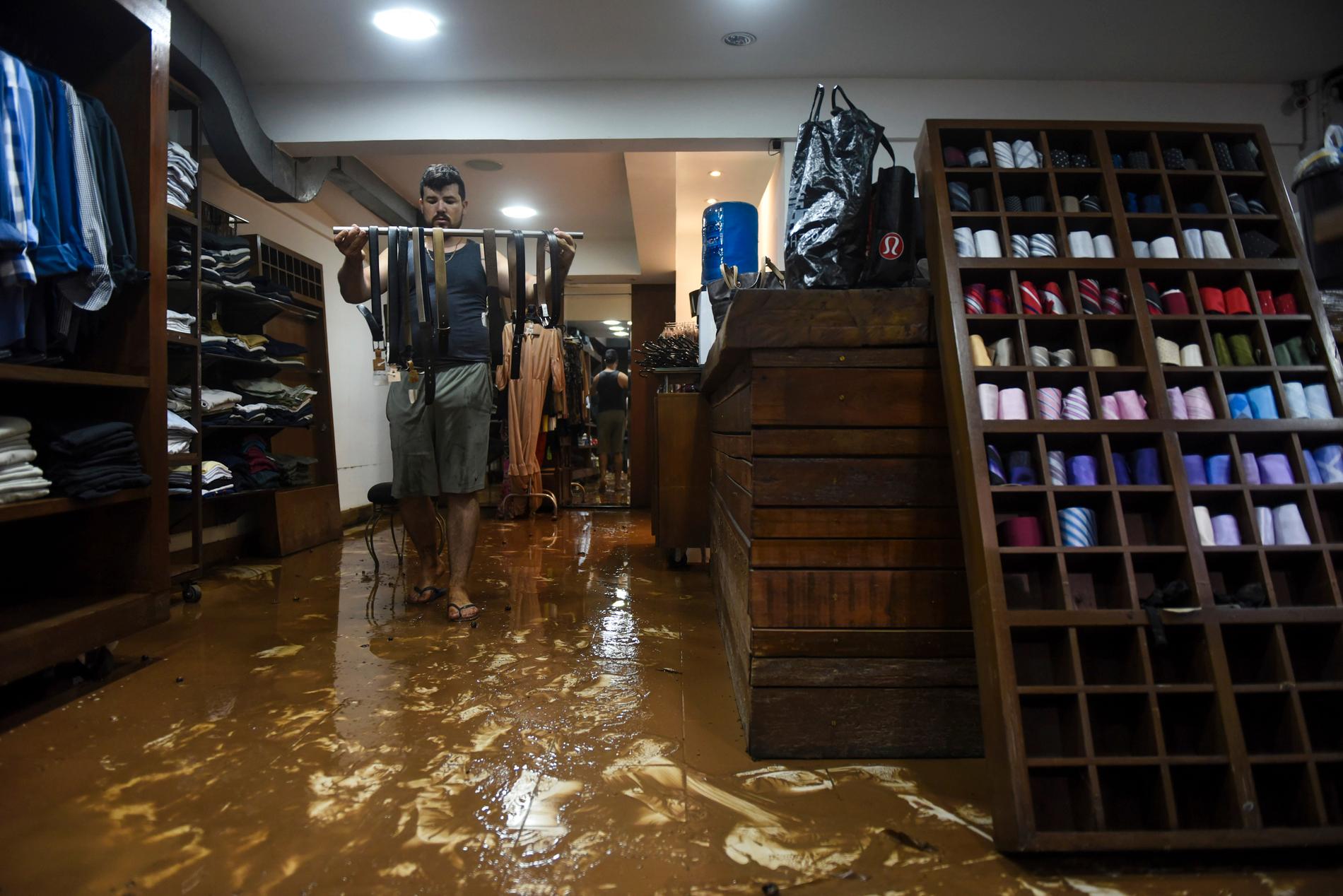 En anställd försöker rädda varor i en översvämmad klädbutik i staden Belo Horizonte i Brasilien.