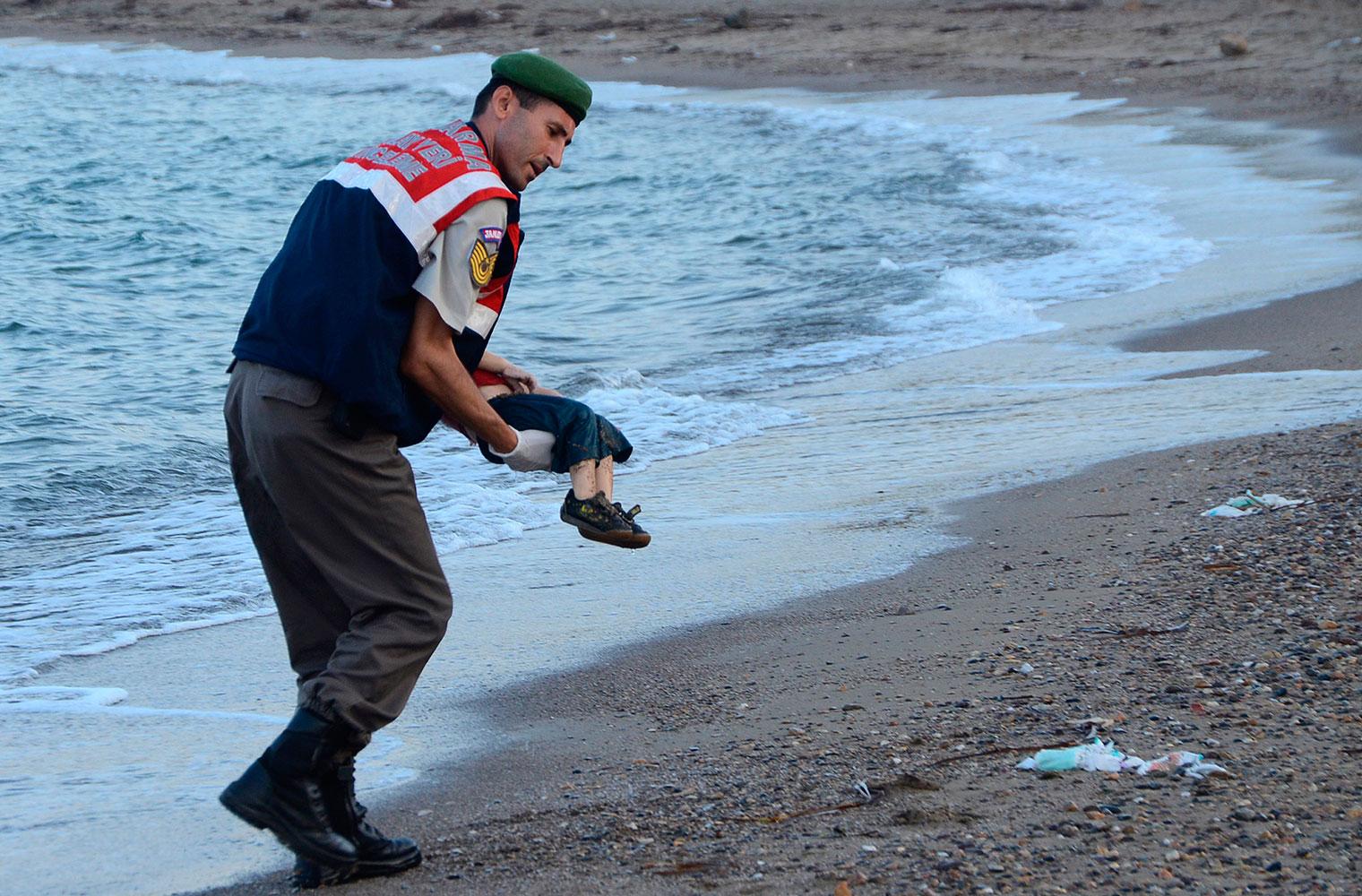 En turkisk gendarm bär bort lille Alans kropp från stranden i turkiska Bodrum för exakt ett år sedan.