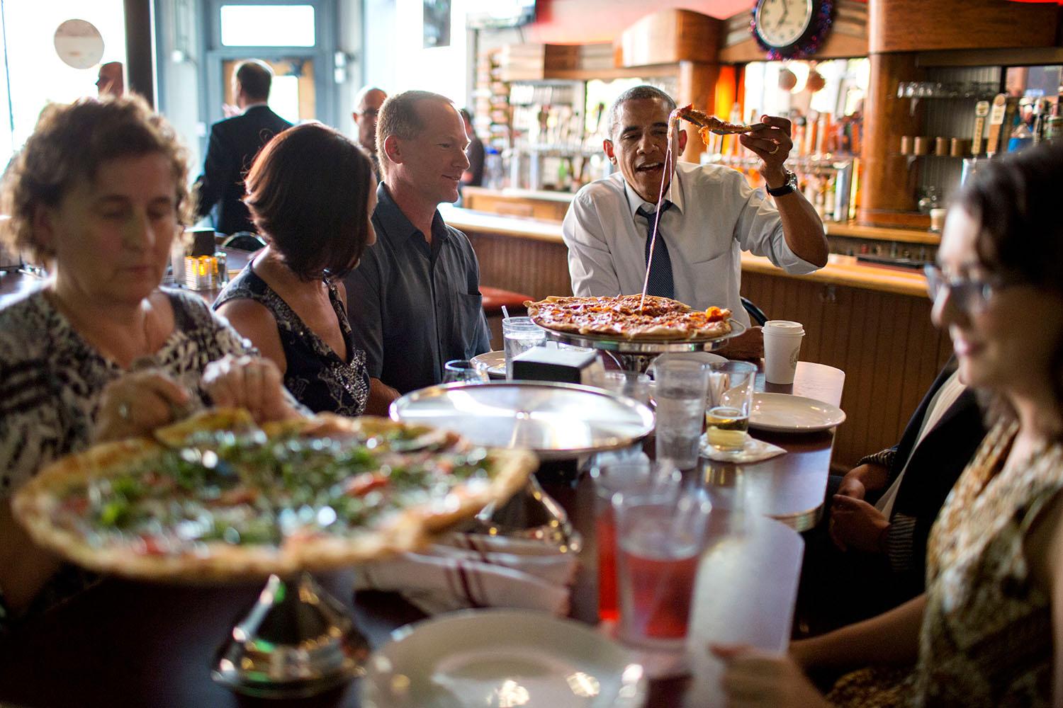 Obama på pizzafest tillsammans med en grupp människor som skrivit brev till presidenten.