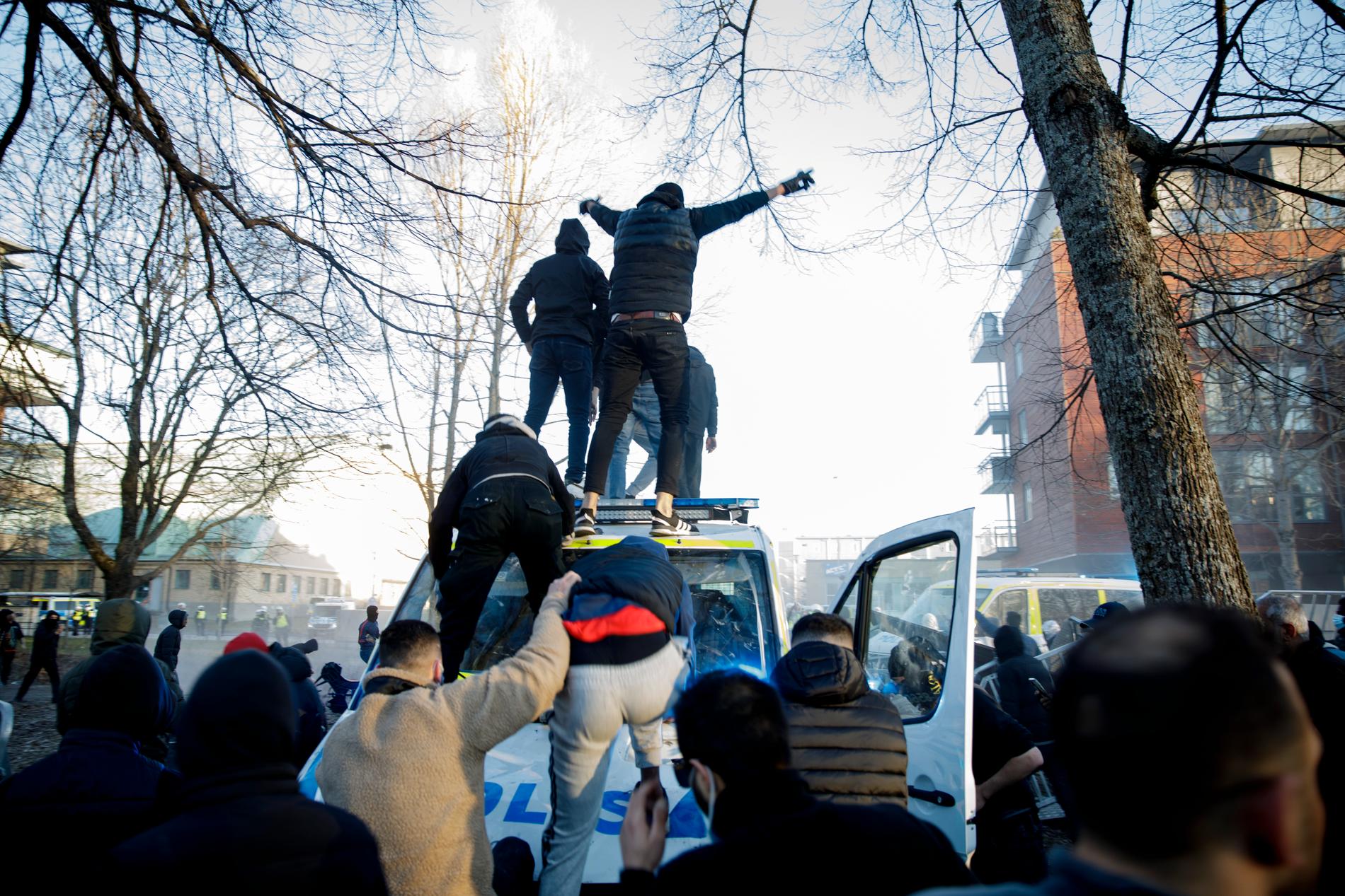 Motdemonstranter klättrar upp på en polisbuss vid Sveaparken i Örebro, där Rasmus Paludan, partiledare för det danska högerextrema partiet Stram kurs, har fått tillstånd för en sammankomst på långfredagen.