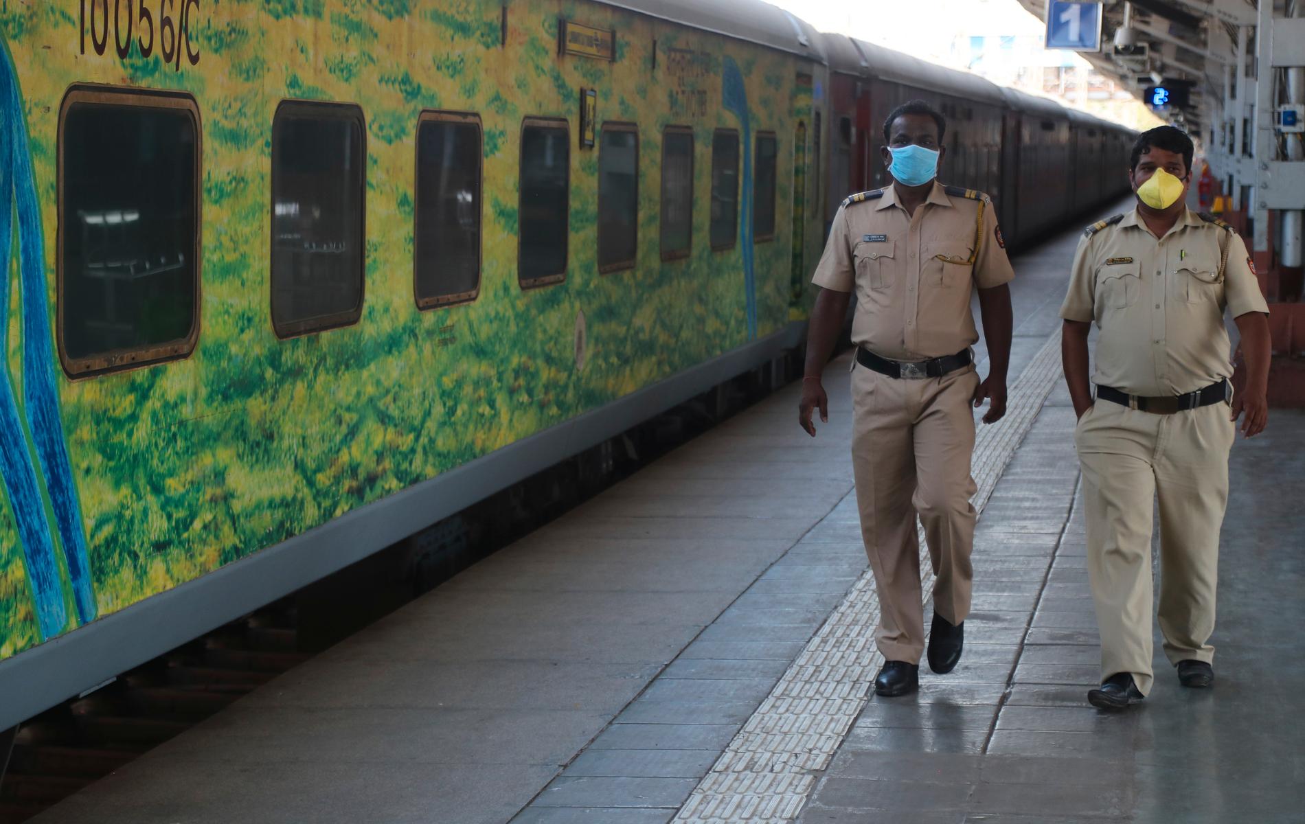 Poliser i munskydd inspekterar en tom tågperrong i Bombay (Mumbai) i Indien.