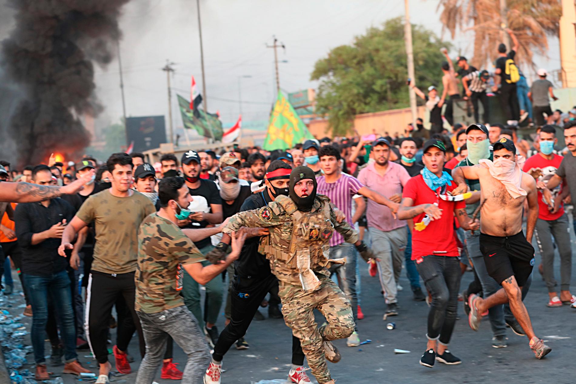 Enligt AP visar bilden en irakisk soldat som får hjälp av demonstranter att fly efter att ha misshandlats av andra demonstranter.