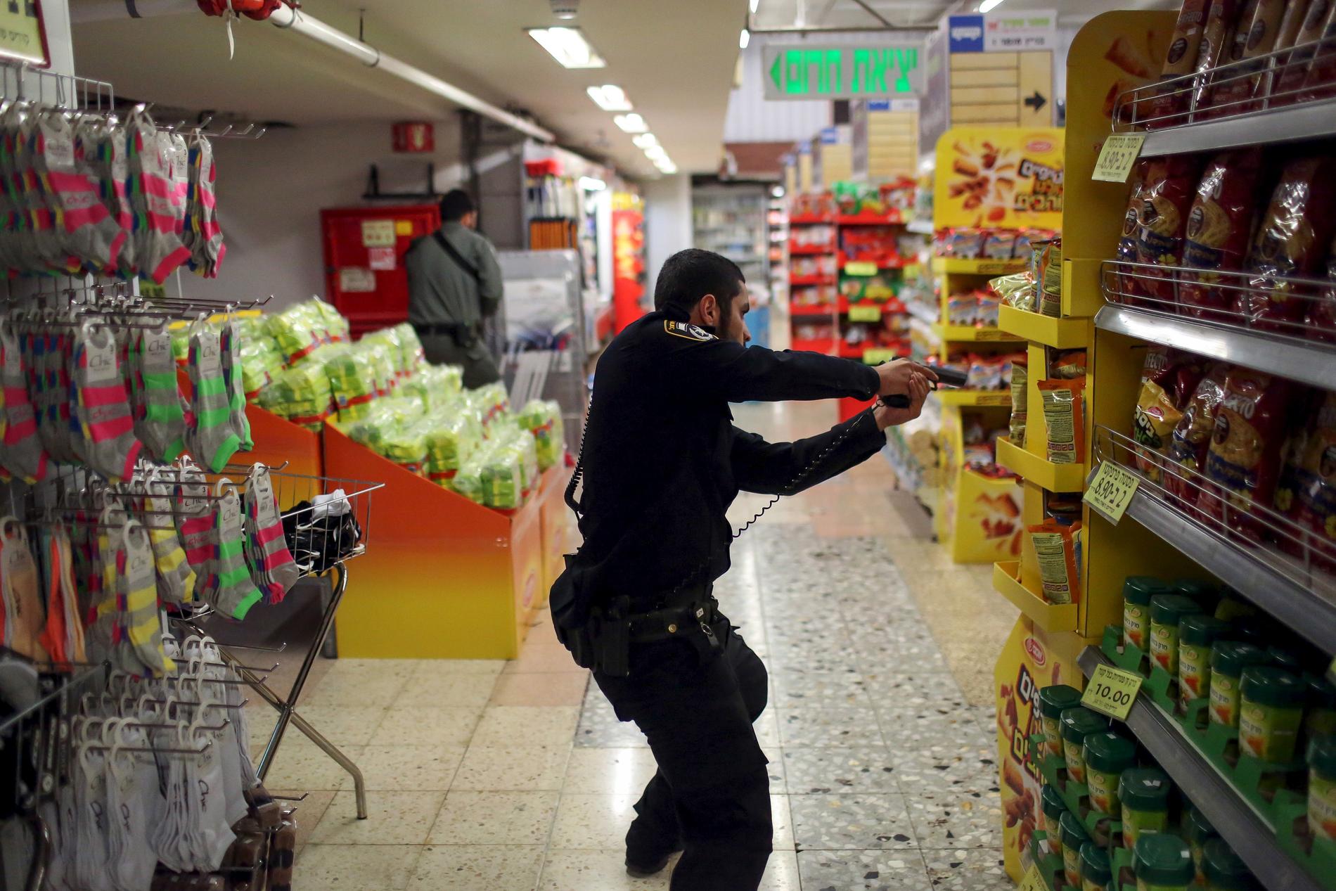 Israelisk polis söker igenom en affär inne i busstationen där en 70-årig kvinna attackerades av en knivman.