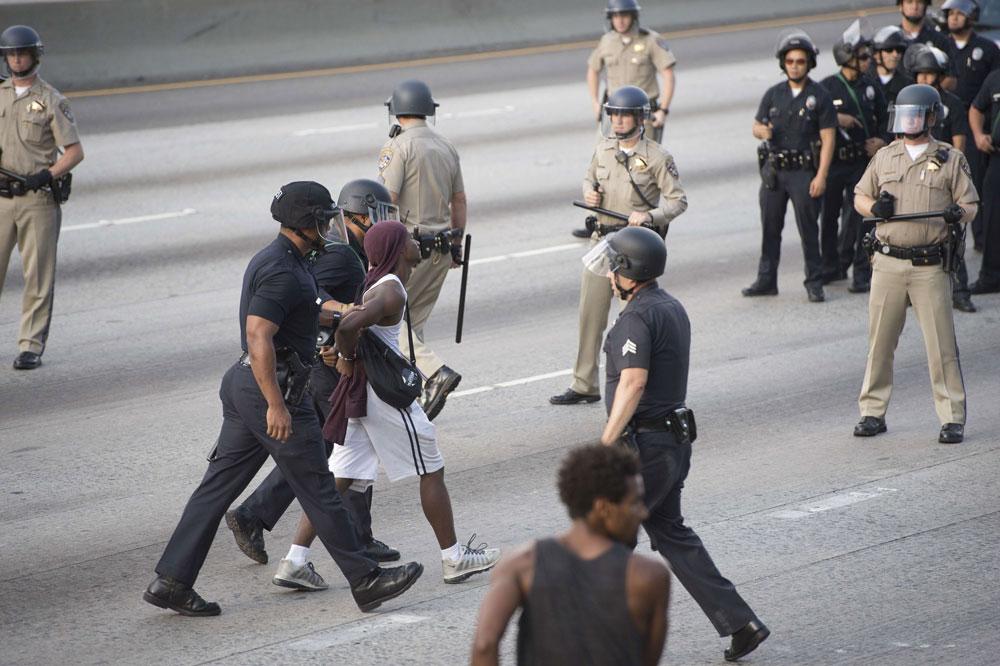 En demonstrant grips av polisen på motorvägen i Los Angeles efter att flera i folksamlingen gått ut på motorvägen och stoppat trafiken.