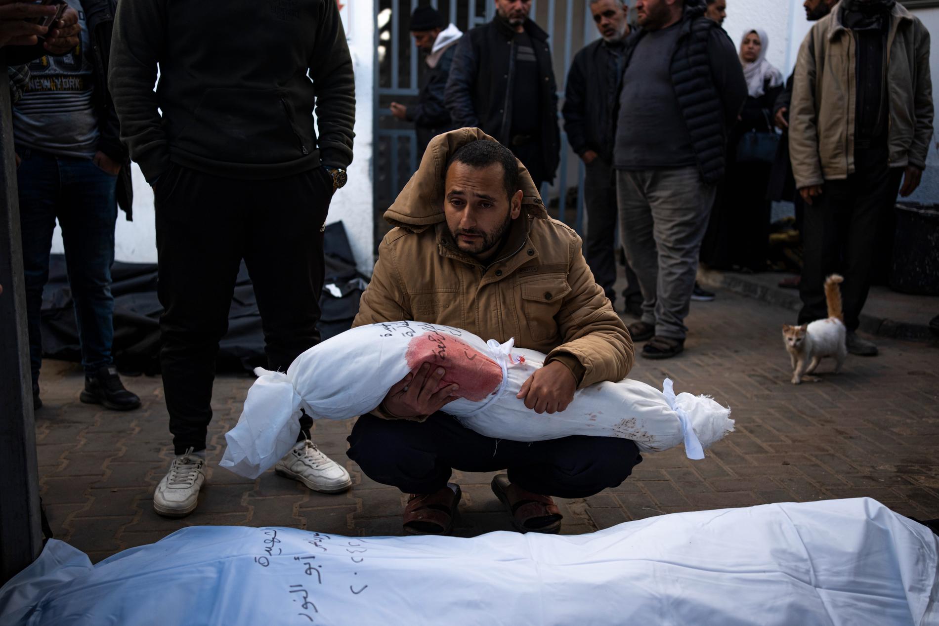 En pappa håller sin döda dotter i sina armar. De är vid bårhuset i Rafah.
