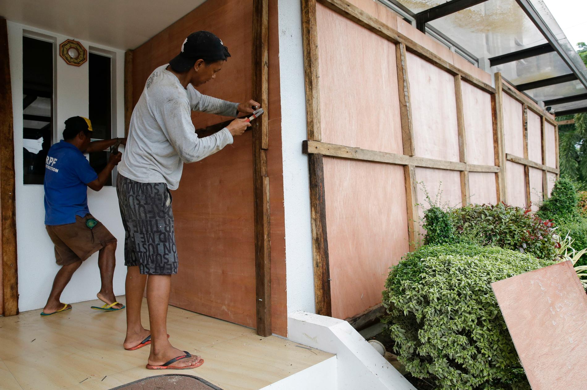 Arbetare täcker för fönstren till ett hotell med plywood-skivor inför tyfonen Mangkhuts framfart.