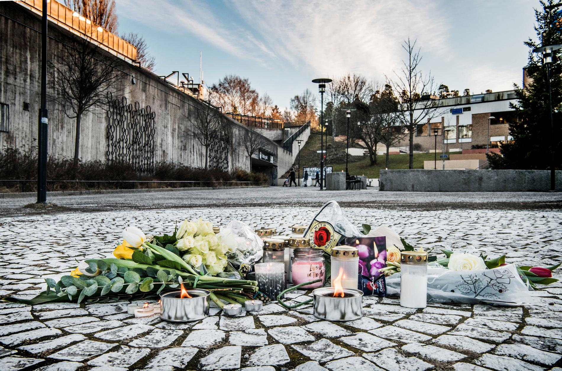 Blommor och ljus på torget i Vårby gård efter att en 63-årig man dödats av en handgranat i februari 2018.