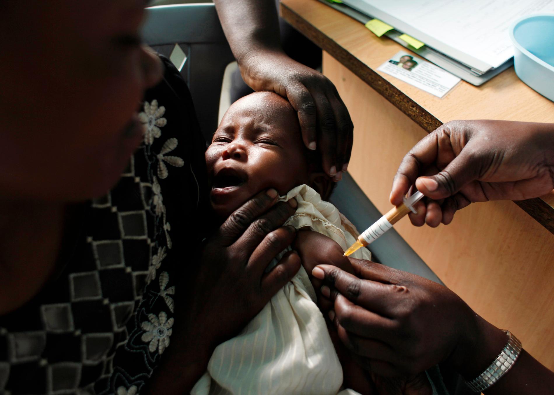 En mamma håller sitt barn medan barnet vaccineras för malaria i Kombewa i västra Kenya. WHO meddelade i augusti 2019 att det är teoretiskt möjligt att utplåna malaria, men inte med de felaktiga vacciner och kontrollmetoder som används för tillfället.