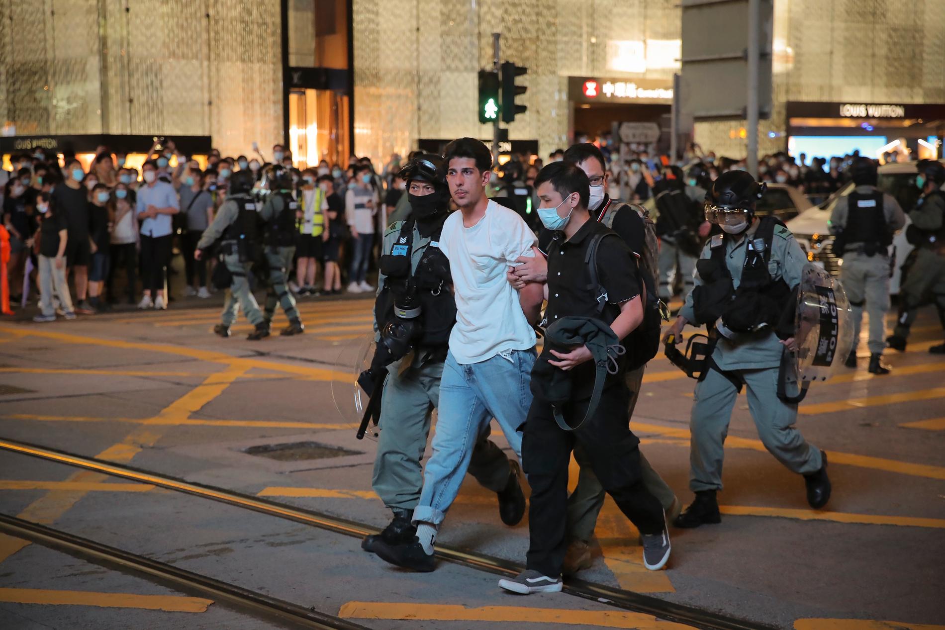 En person förs bort av polis i samband med demonstrationerna i Hongkong på tisdagskvällen.