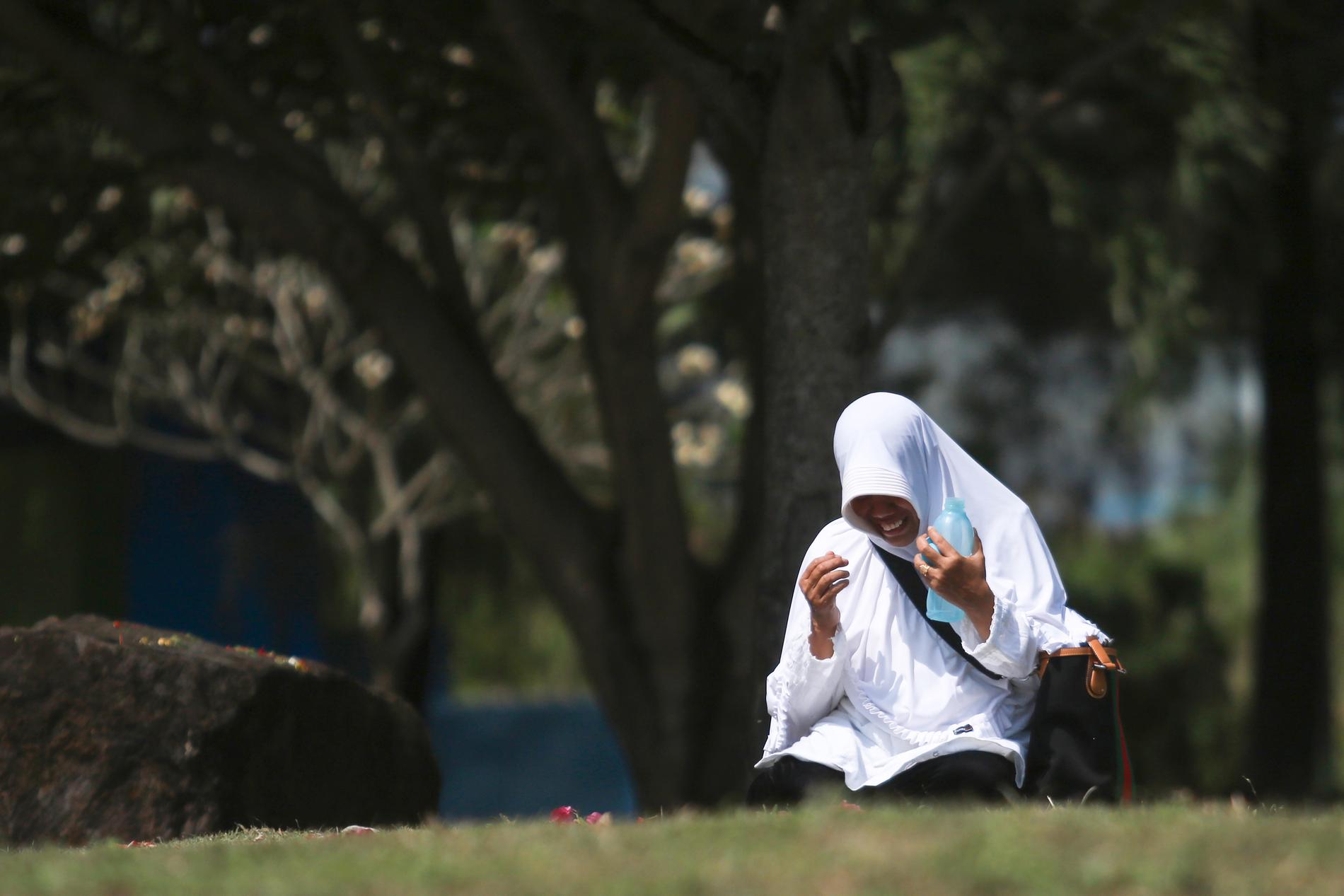 En kvinna ber vid en massgrav i Banda Aceh i Indonesien på torsdagen.