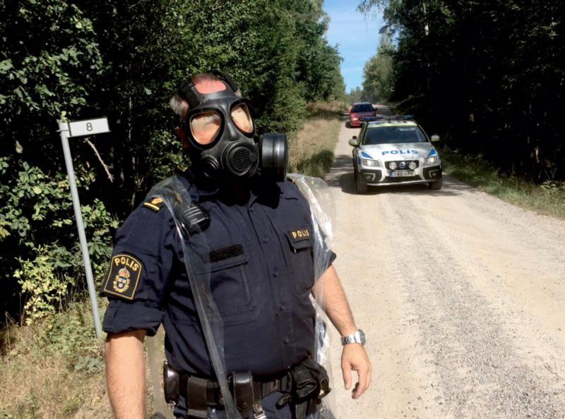 En polisman med en gasmask vid avspärrningarna vid Möljeryd utanför Ronneby, där ett Jas Gripenflygplan kraschade under förmiddagen.
