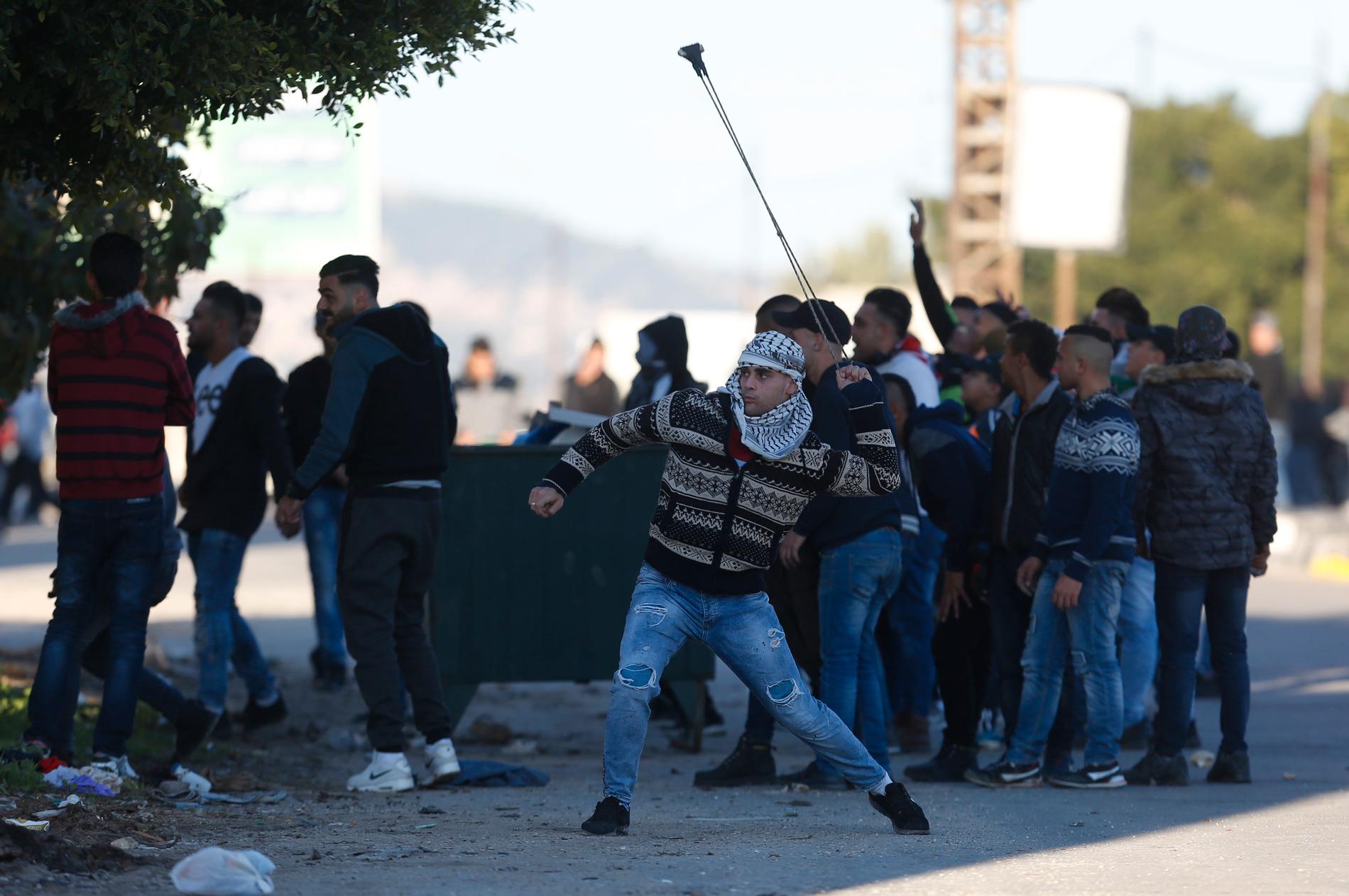 En palestinsk demonstrant kastar sten under sammandrabbningar med israeliska soldater på fredagen. Arkivbild.