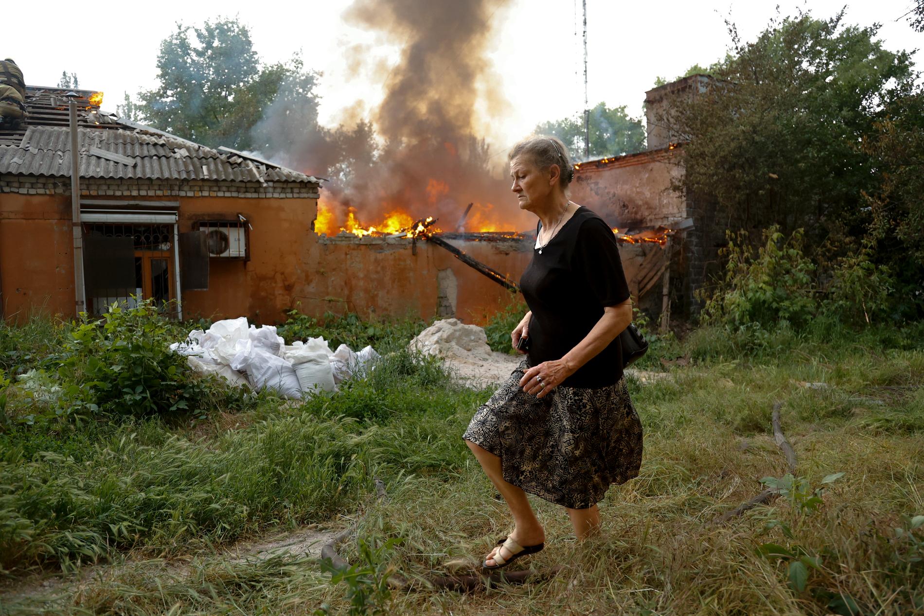En kvinna flyr från ett hus som brinner efter beskjutning i Donetsk.