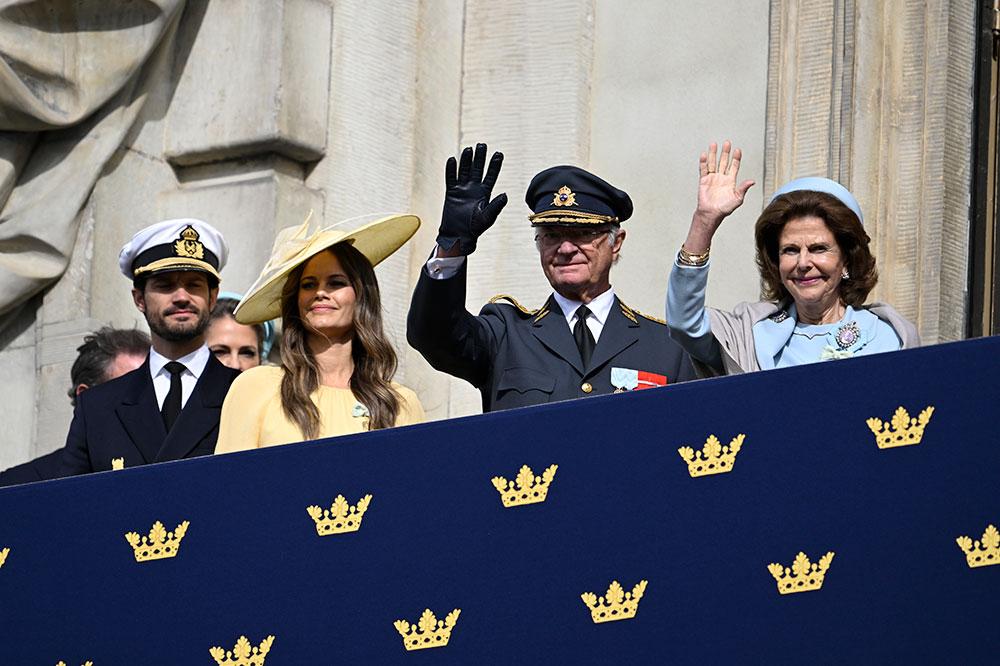 Kungaparet och prins Carl Philip och prinsessan Sofia vinkar från Kungliga slottets balkong. 