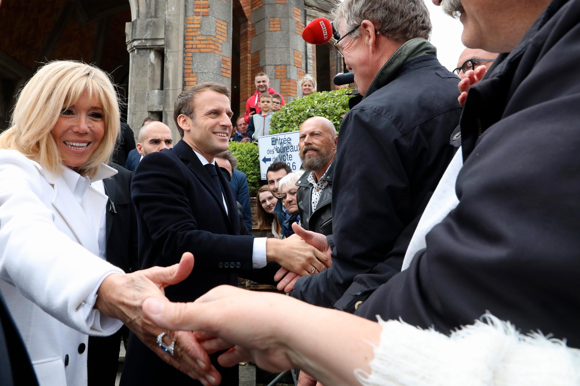 Frankrikes president Emmanuel Macron och hans hustru Brigitte Macron skakar hand med väljare efter att ha röstat i Le Touquet i norra Frankrike.