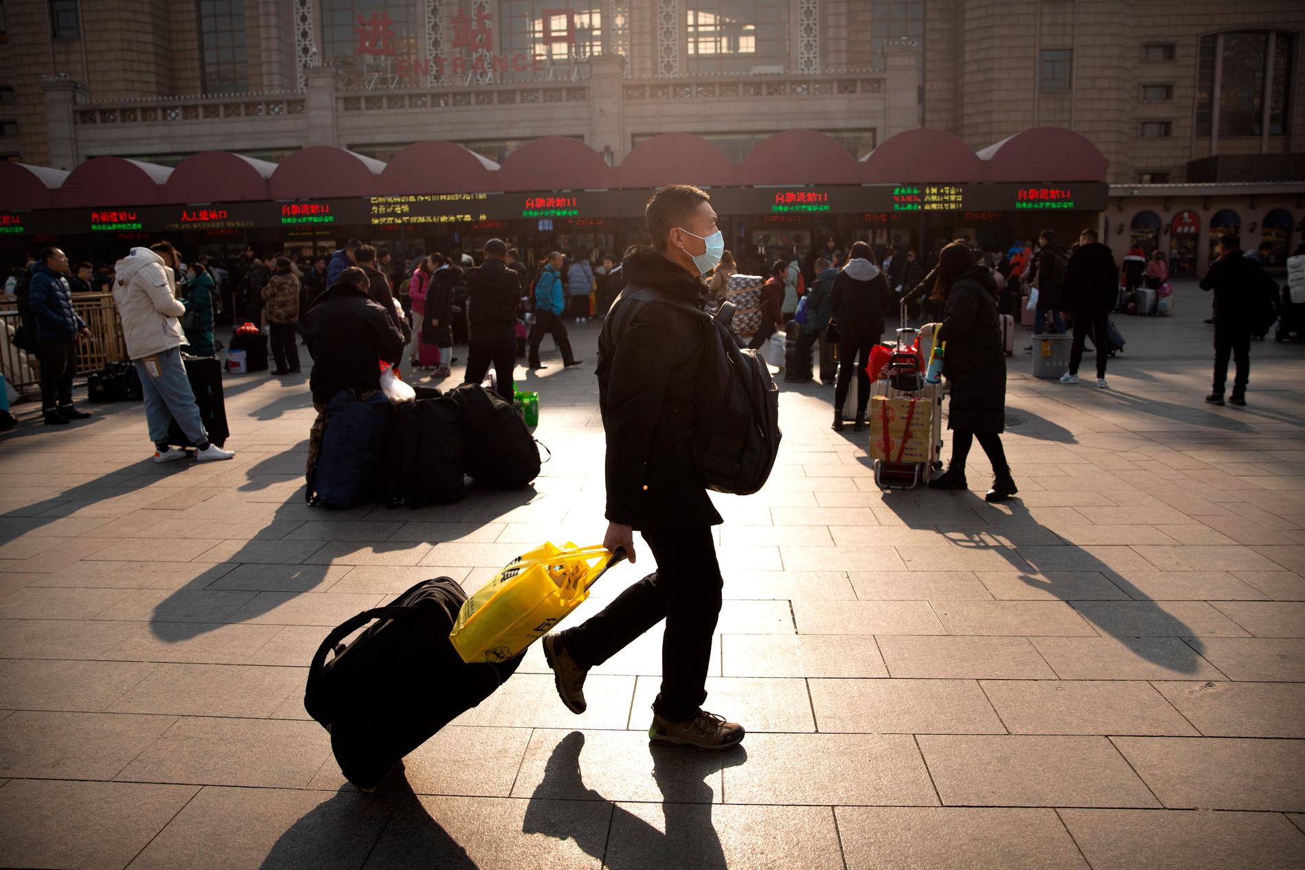 En man med ansiktsmask framför Pekings tågstation under fredagsmorgonen. Två personer har nu dött av det sars-liknande viruset.