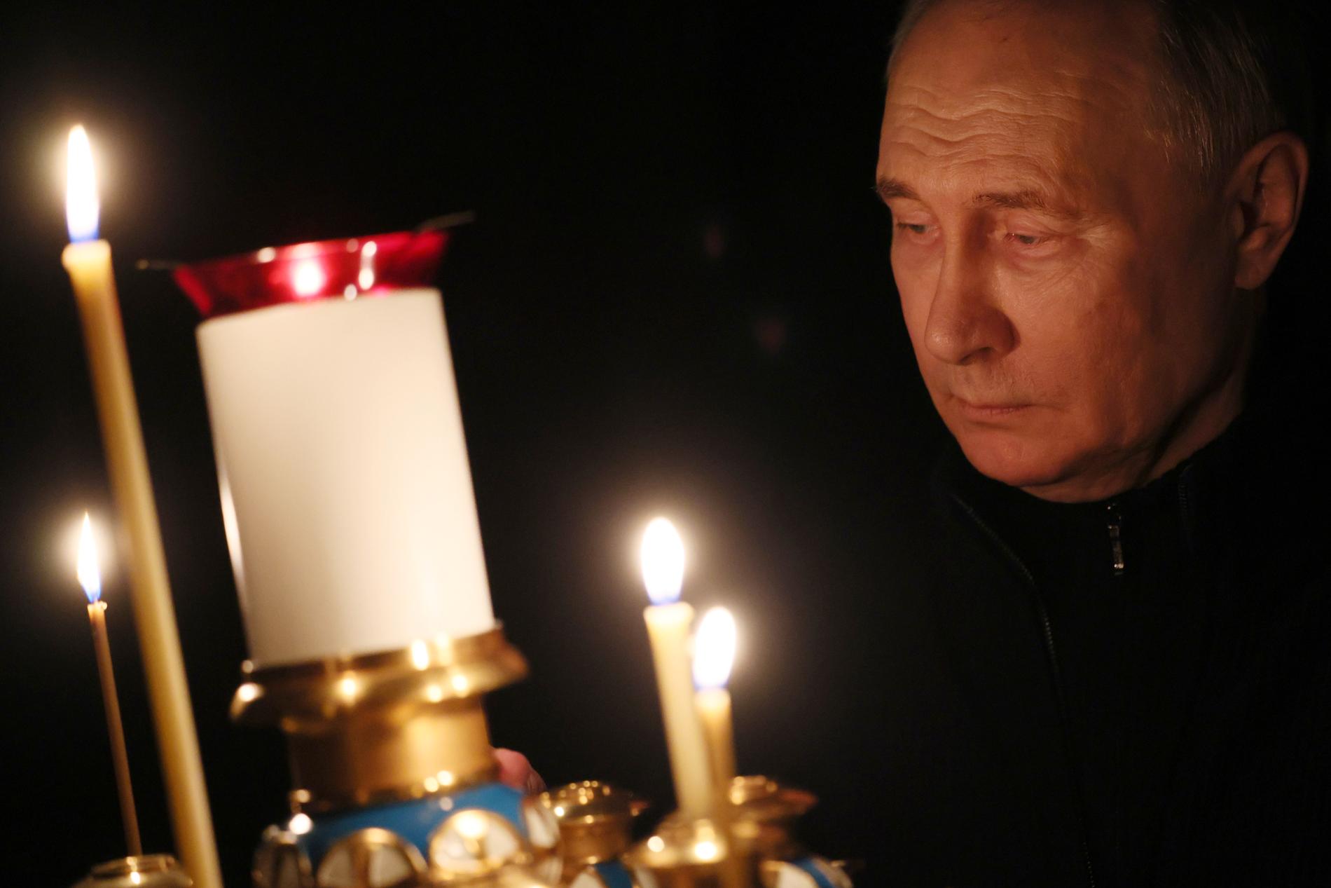 Putin tänder ett ljus till minne av offren i terrorattacken. 