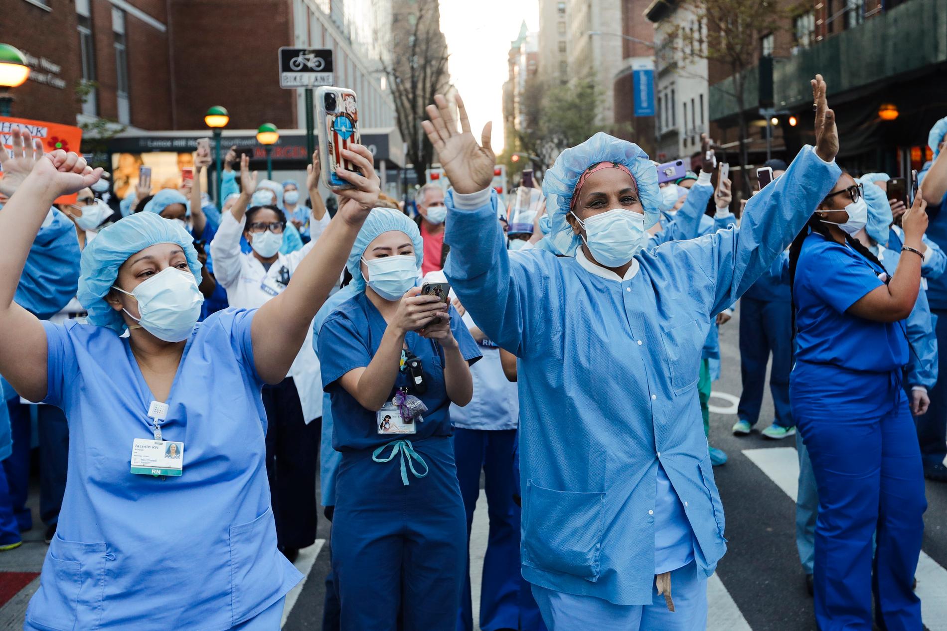 Vårdpersonal i pandemins frontlinje i New York hyllas utanför sjukhuset Lenox Hill i New York tidigare i år. Nu kan deras jobb vara hotade – om det väljer att inte vaccinera sig.