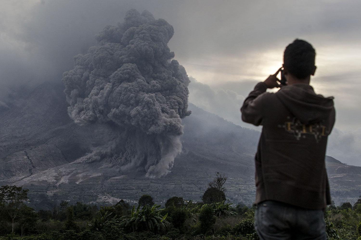 En man fotograferar Mount Sinabung.