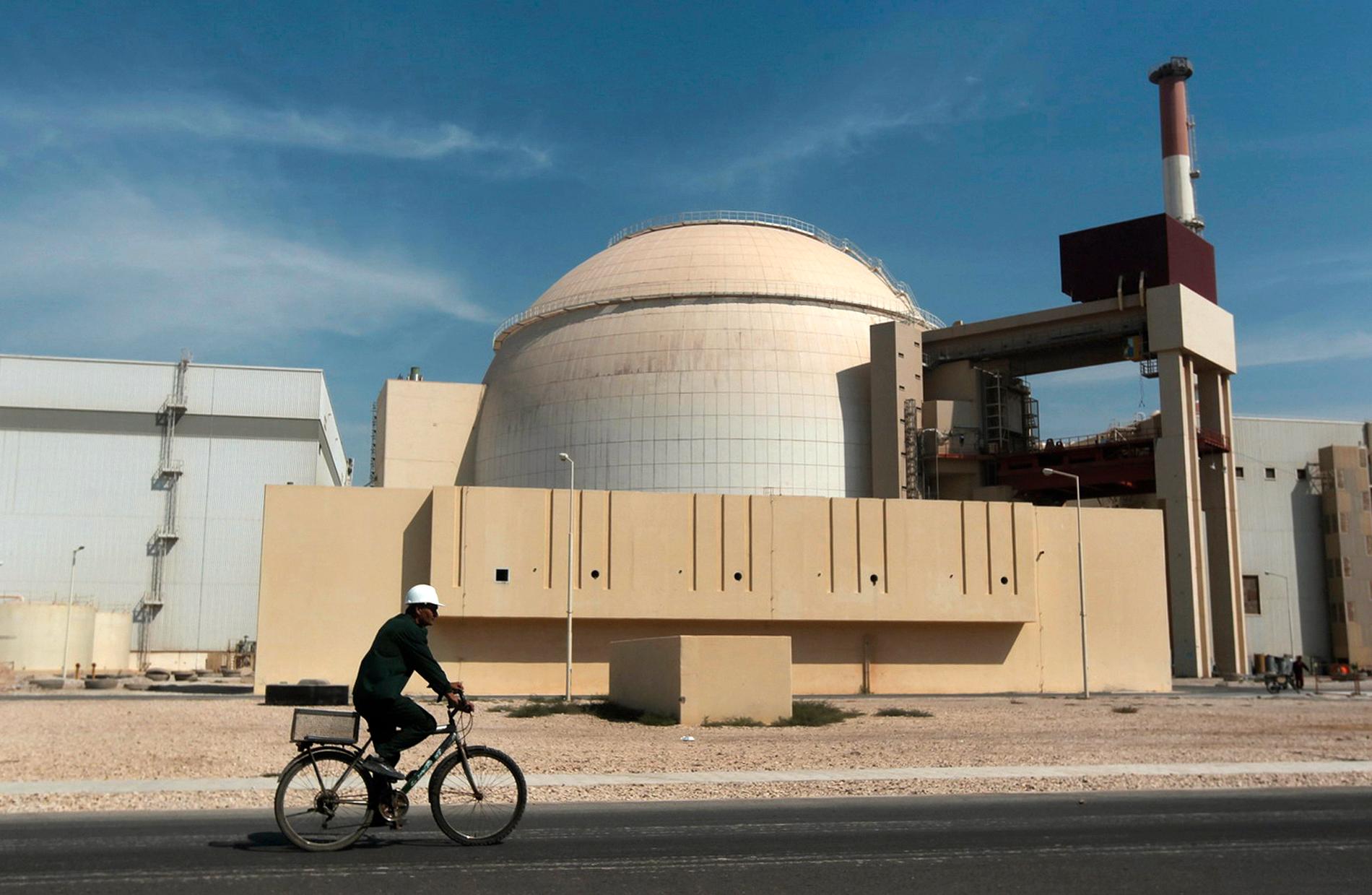 En man cyklar förbi en kärnkraftreaktor utanför staden Bushehr i Iran. Arkivbild.
