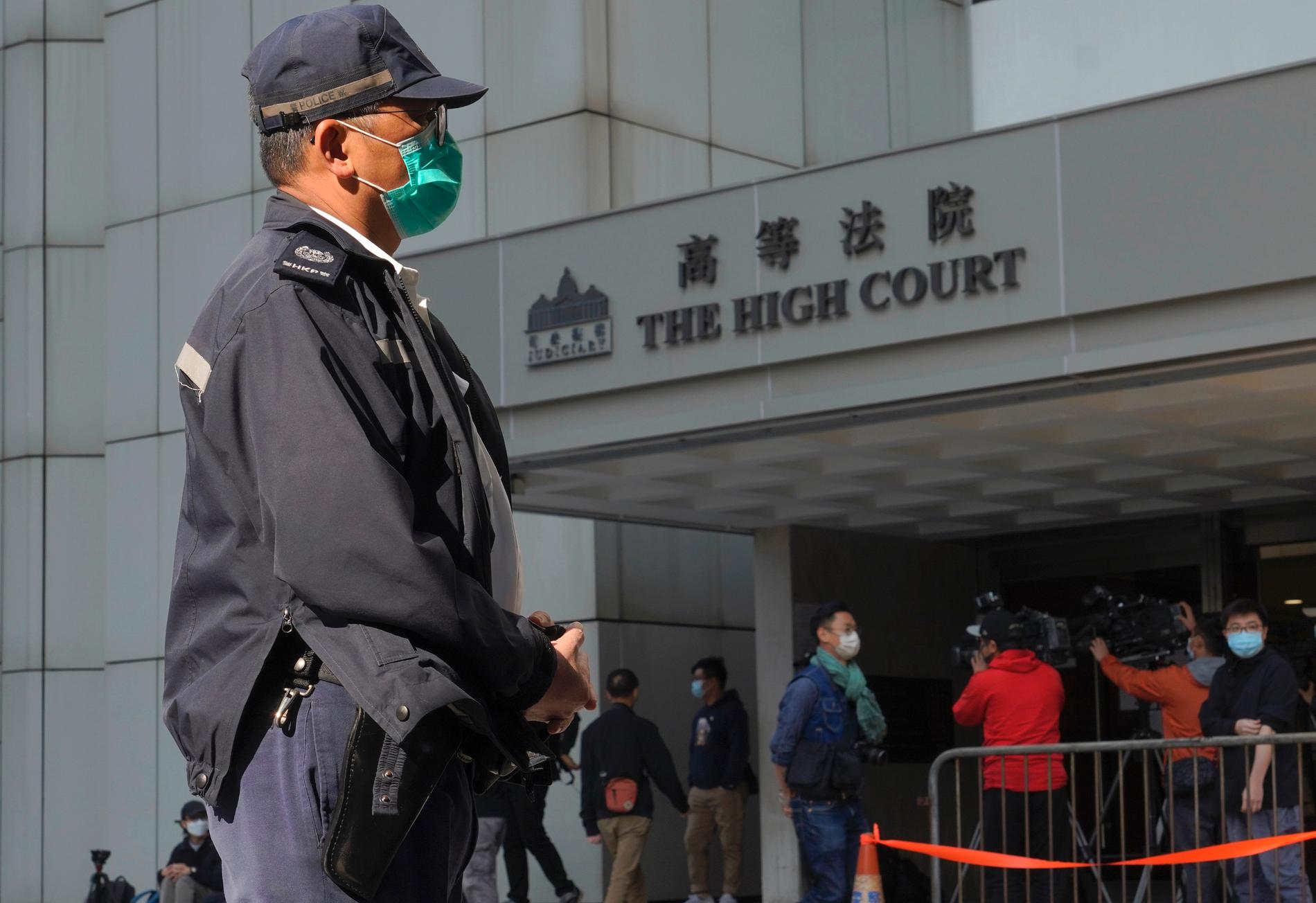 En polis står vakt utanför en domstol i Hongkong. 47 demokratiaktivister åtalas i den största rättegången hittills enligt linje med Kinas så kallade säkerhetslag. Arkivbild.