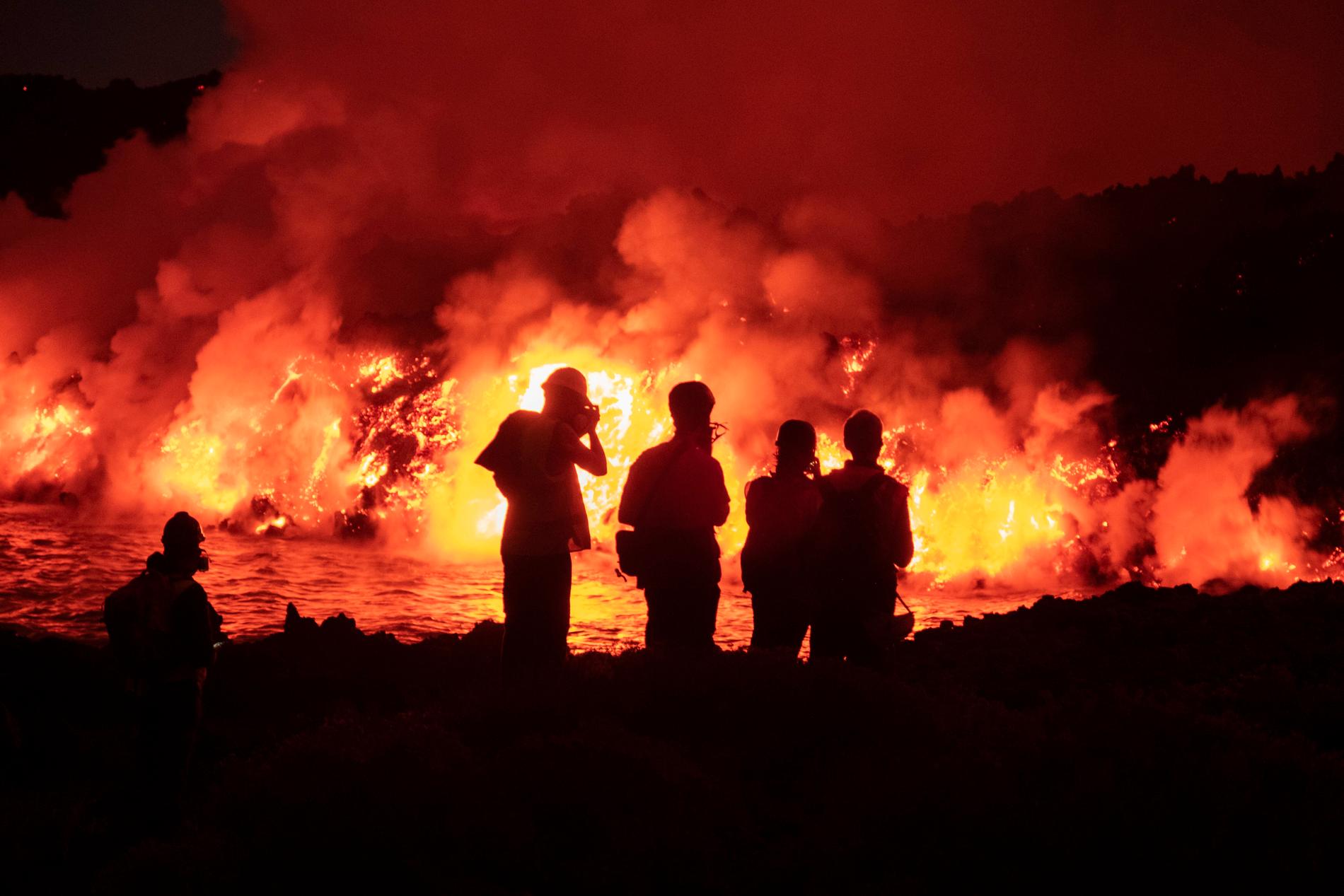 En grupp vetenskapsmän ser lava som strömmar ut från vulkanen på La Palma.  