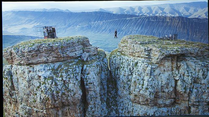 STORSLAGET Ett av biennalens mer dramatiska bidrag är Taus Makhachecas film där en man går på lina och sakta flyttar en målning från ena sidan av en ravin till den andra.