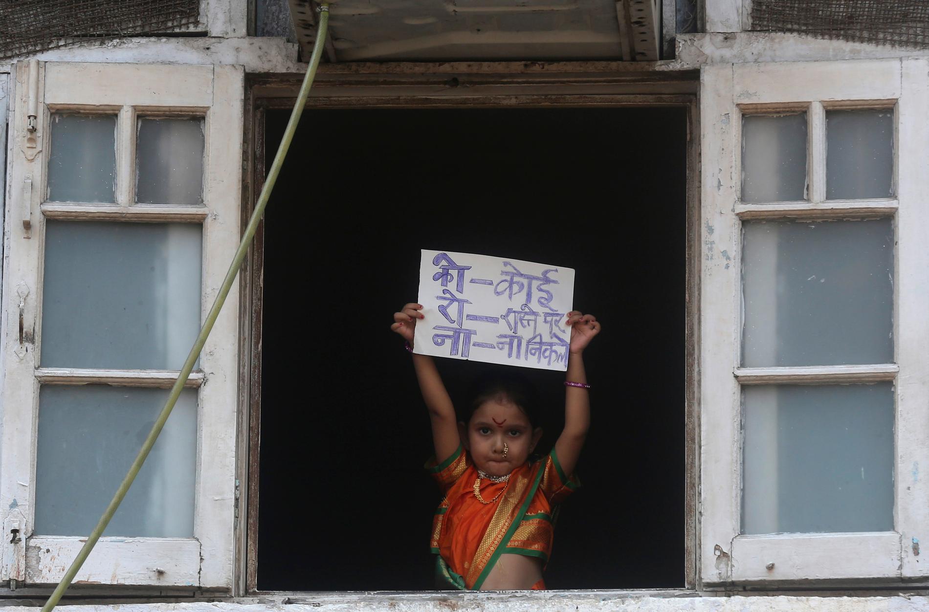 MUMBAI, INDIEN En liten flicka i traditionell klädsel håller en skylt som säger – ingen ska gå ut.