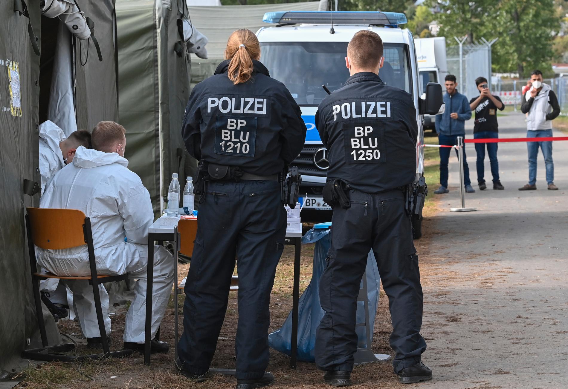 Tyska poliser väntar på migranter vid Central Initial Reception Centre for Asylum Seekers (ZABH) i delstaten Brandenburg i Eisenhuettenstadt, Tyskland. Tyska myndigheter säger att antalet migranter som anländer till landet via Polen och Vitryssland har ökat kraftigt de senaste månaderna.