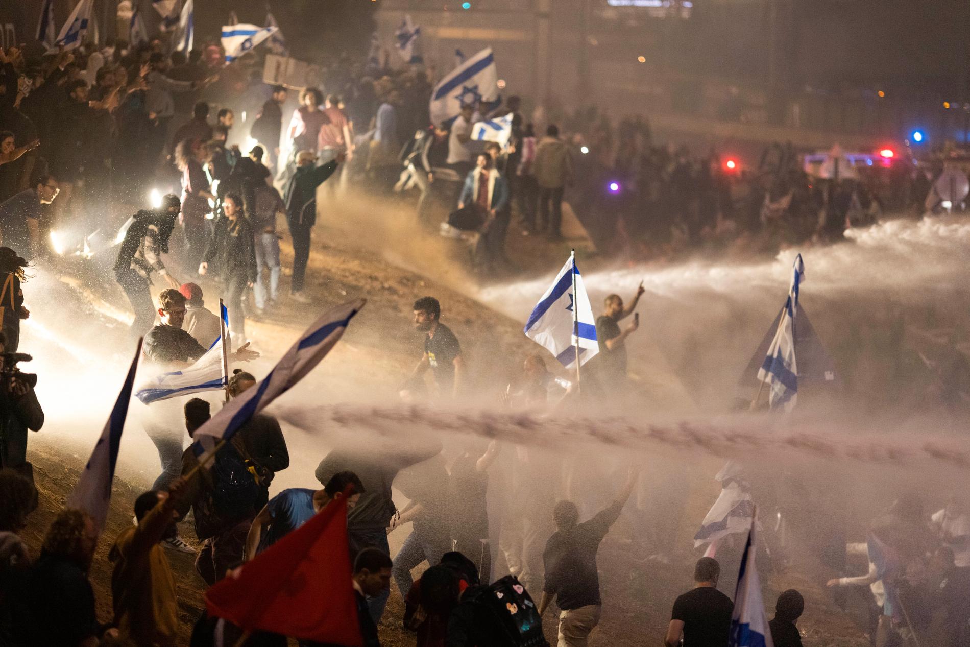 Israelisk polis använde vattenkanoner för att skingra demonstranter som blockerade en motorväg under gårdagskvällens protester mot regeringens planer.