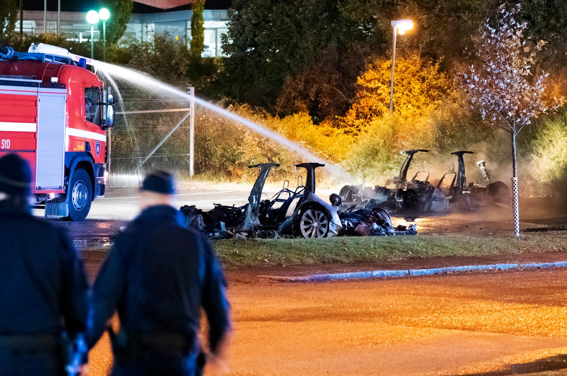 Polis och räddningstjänst på plats vid vraken efter de utbrända elbilarna utanför Teslas servicecenter i Malmö tidigt på tisdagsmorgonen.