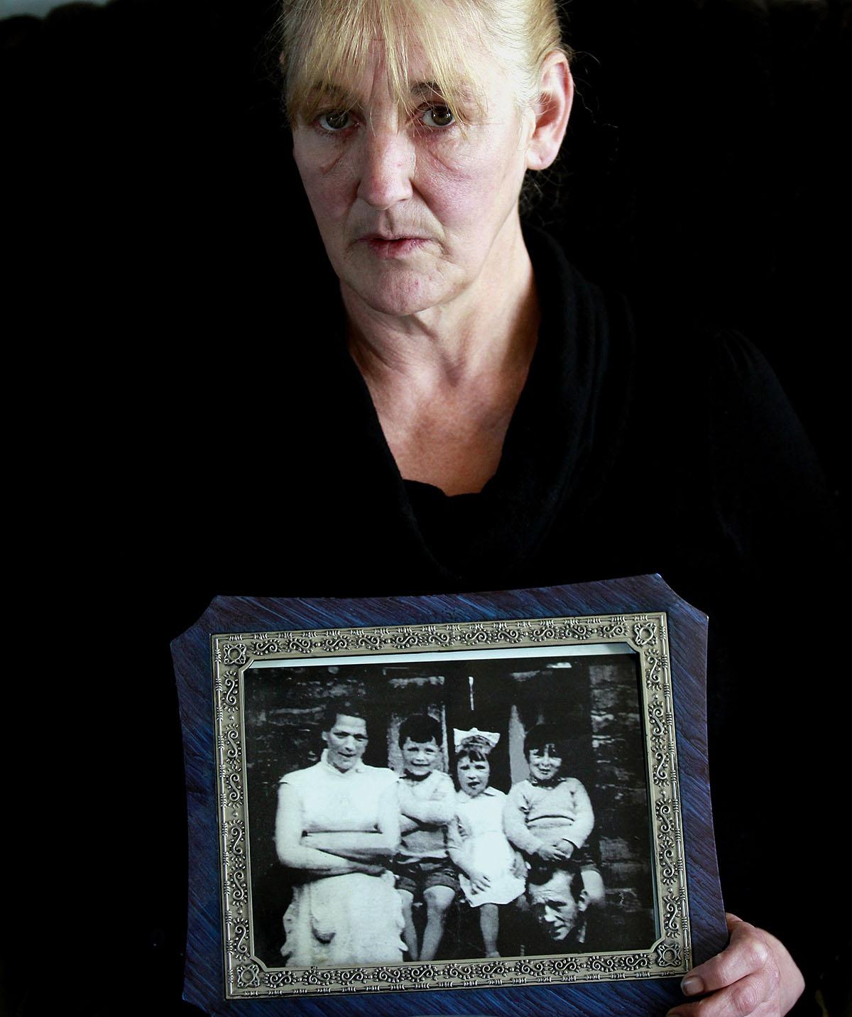 Helen McKendry håller upp ett familjefoto. Längst till vänster syns hennes mamma Jean McConville vars försvinnande utgör ramen för ”Säg inget”.