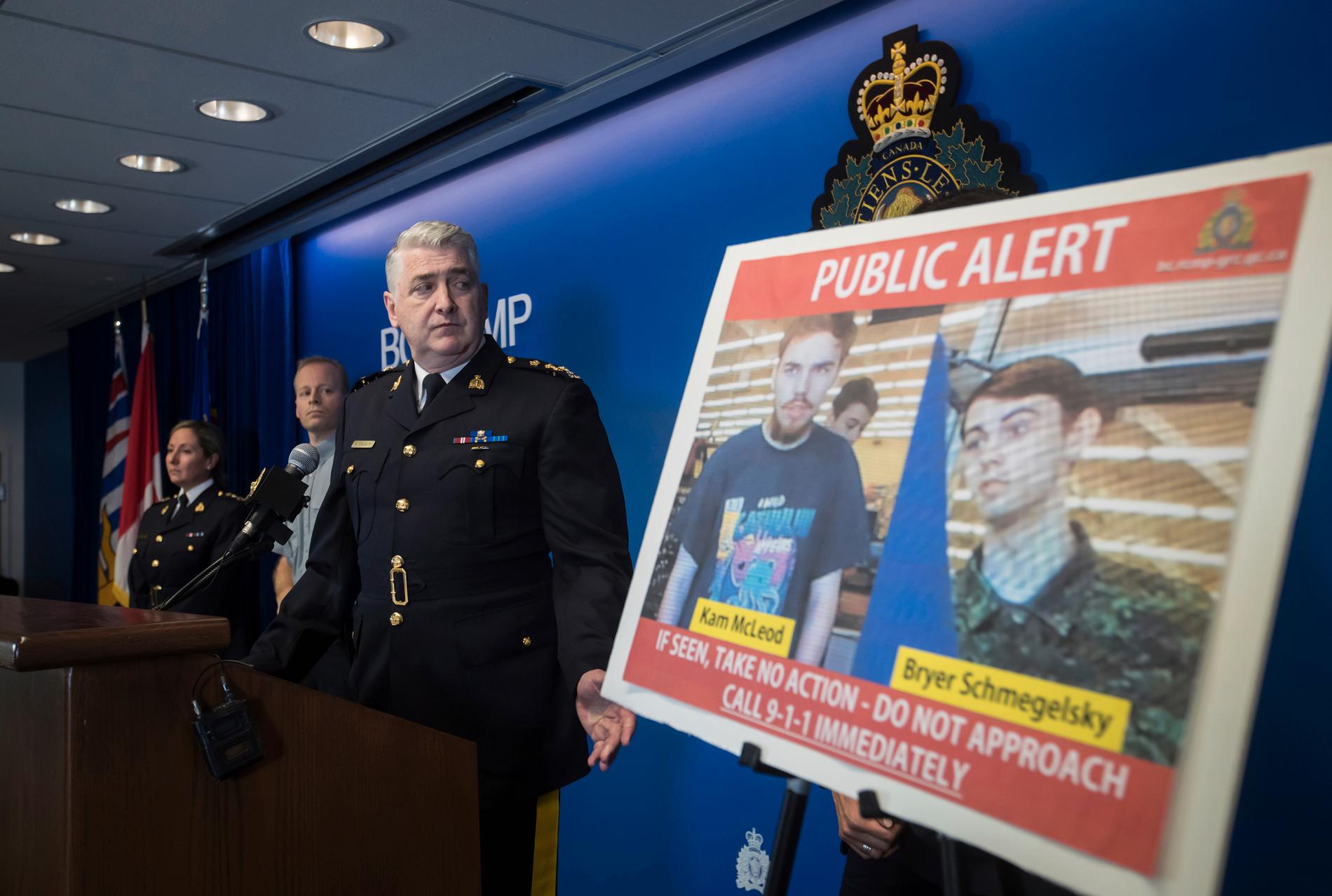 Polisen Kevin Hackett visar upp bilder på de två eftersökta männen under en presskonferens i Surrey. 