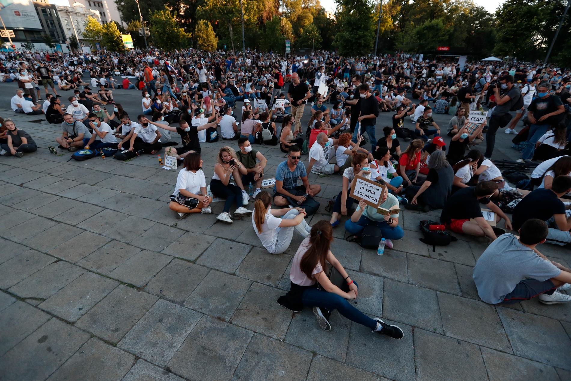 Sittande demonstranter utanför det serbiska parlamentet i torsdags kväll. De serbiska myndigheterna har skrotat sina planer på att införa utegångsförbud i landet men har, efter dagar med våldsamma demonstrationer, infört förbud mot samlingar med fler än tio personer.