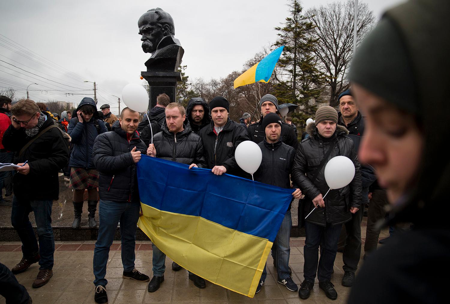 För Ukraina! Pro-Ukrainska demonstranter framför en staty av ukrainske poeten Taras Sjevtjenko i Simferopol, fredag 7 mars.