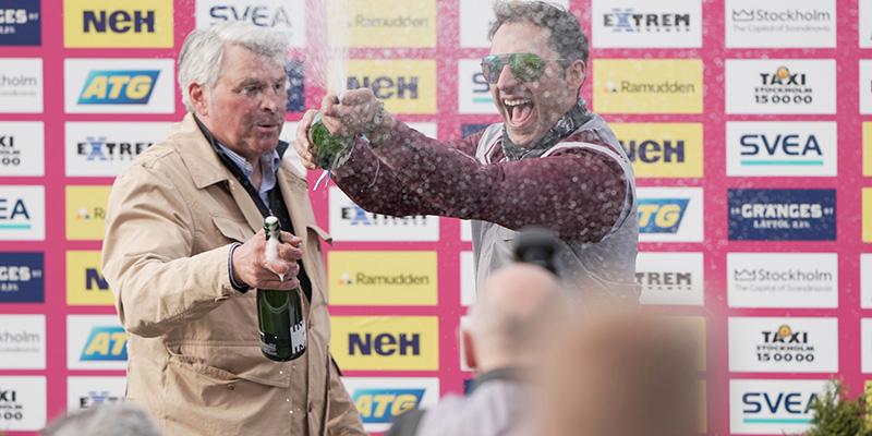 Gabriele Gelormini och Hohnecks tränare, Phillipe Allaire, firar med champagne efter storsegern på Solvalla.