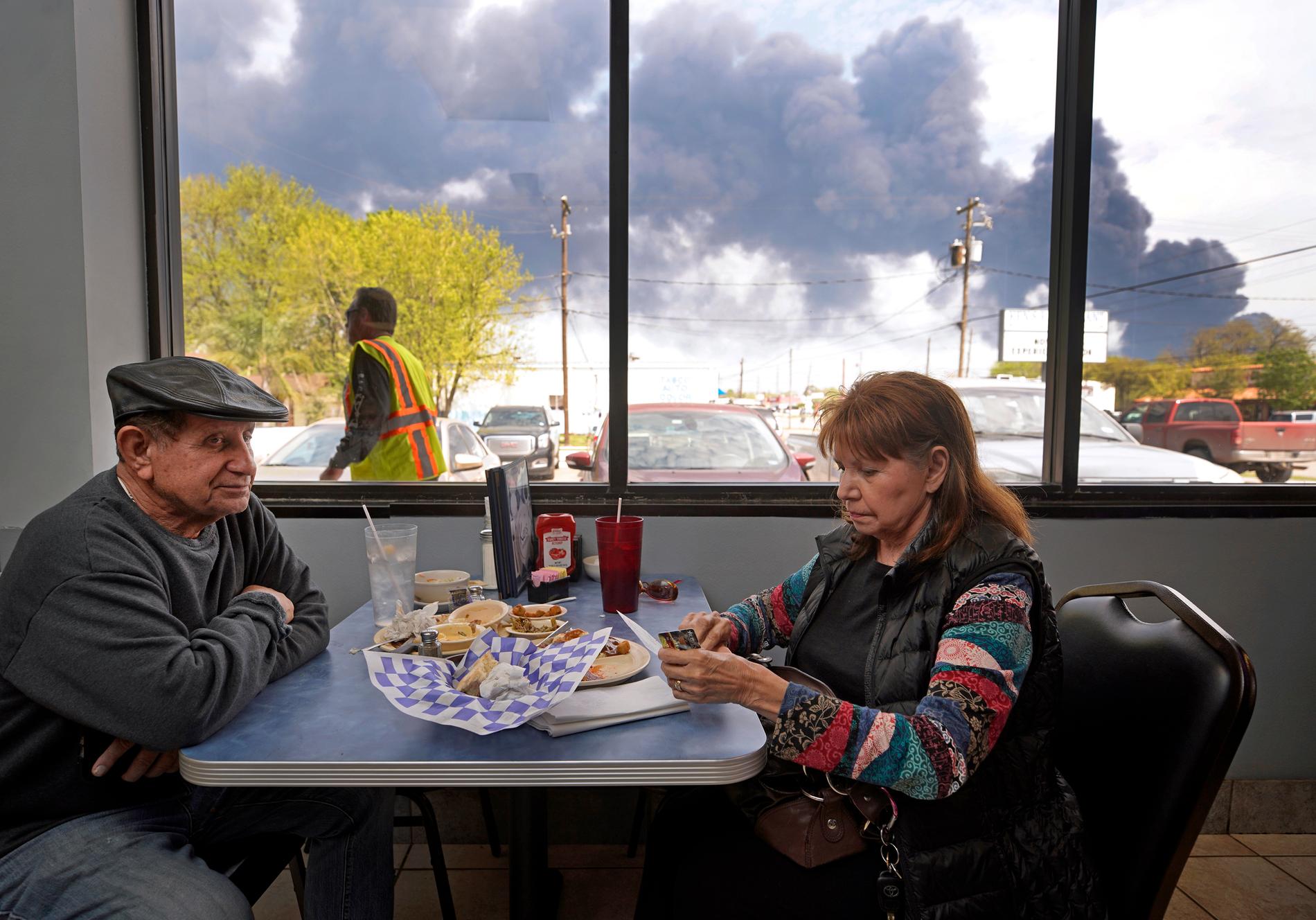 Charlie och Dalia Tamez äter lunch på en restaurang i amerikanska Houston, Texas, medan rök bolmar ut från branden.