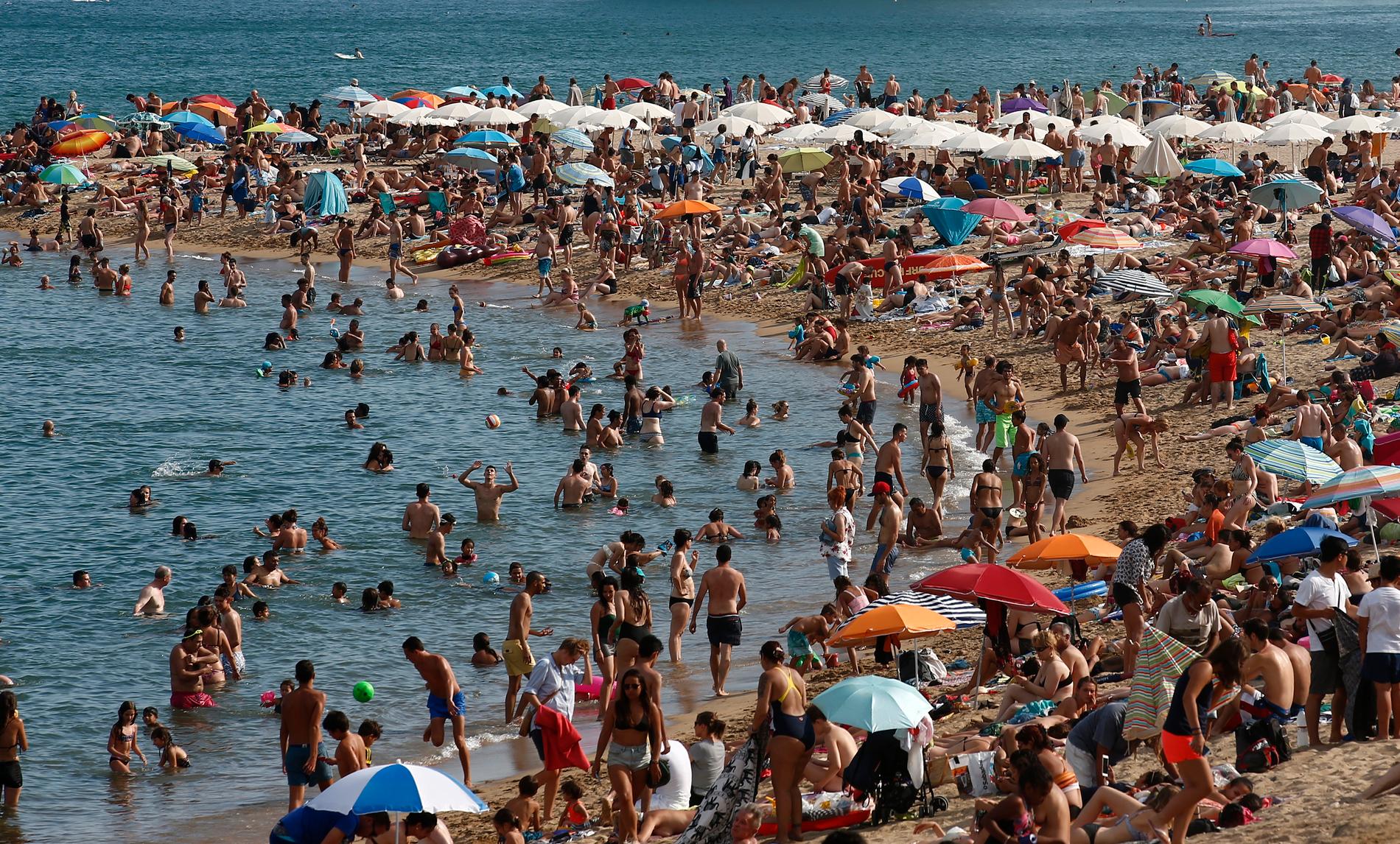 Människor säker svalka på stranden i Barcelona.